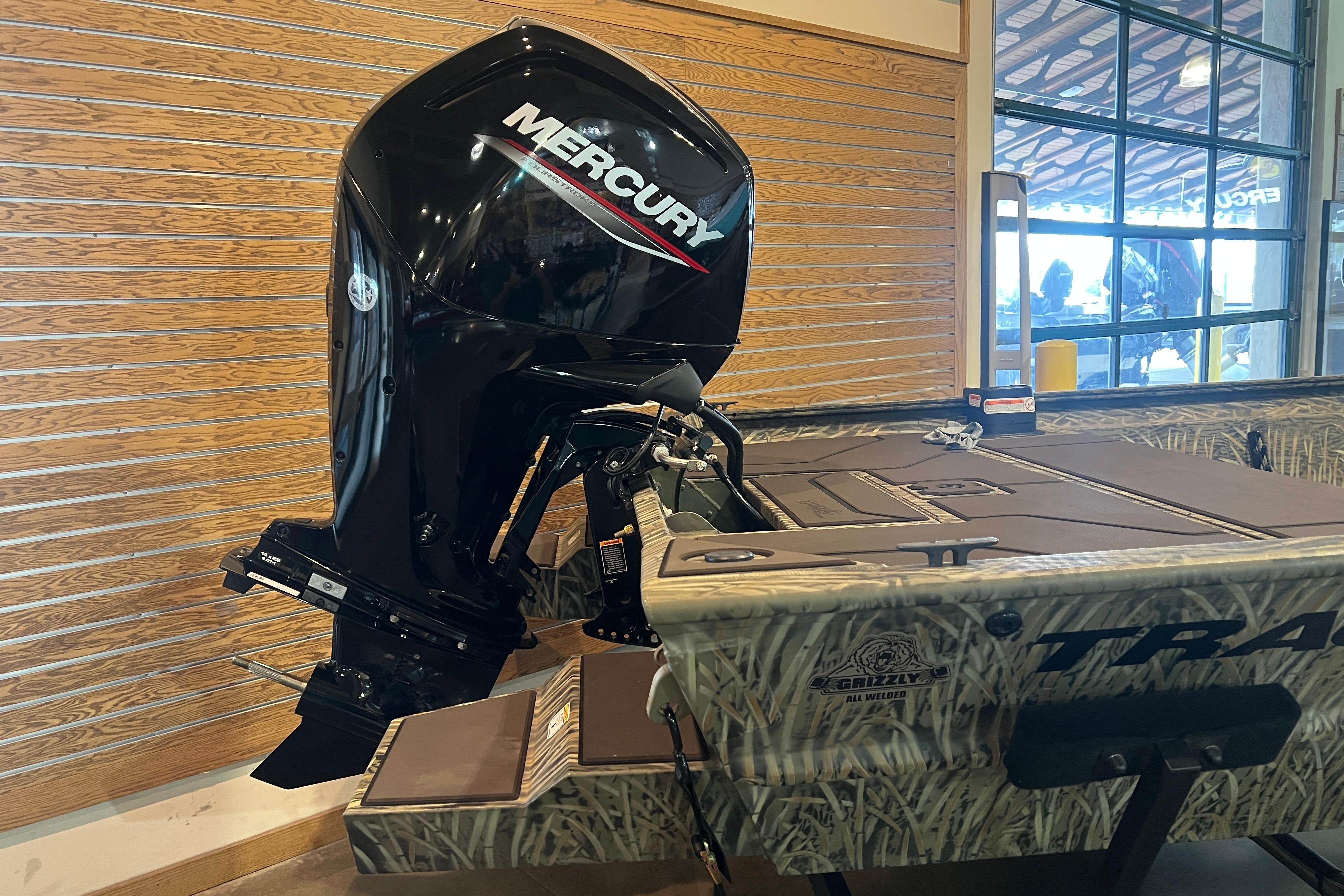 2026 Tracker Grizzly 1860 CC boat with Mercury outboard motor in showroom.