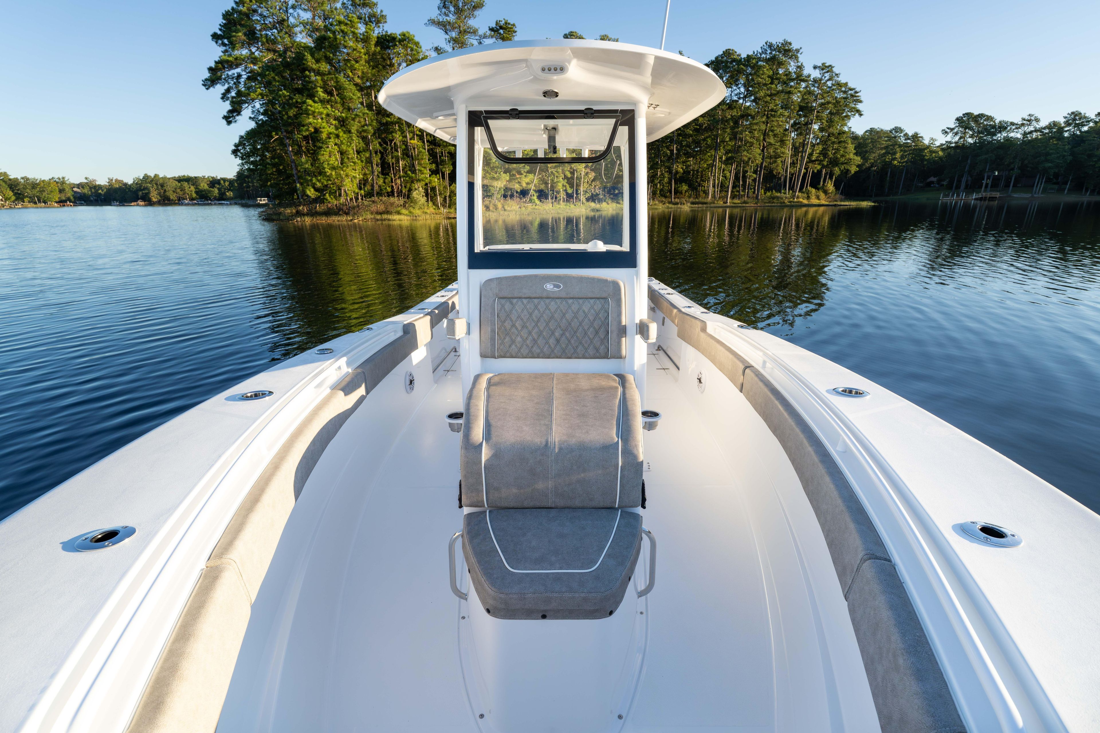 2026 Sea Hunt Ultra 275 Coffin Box boat on serene lake with forest backdrop.