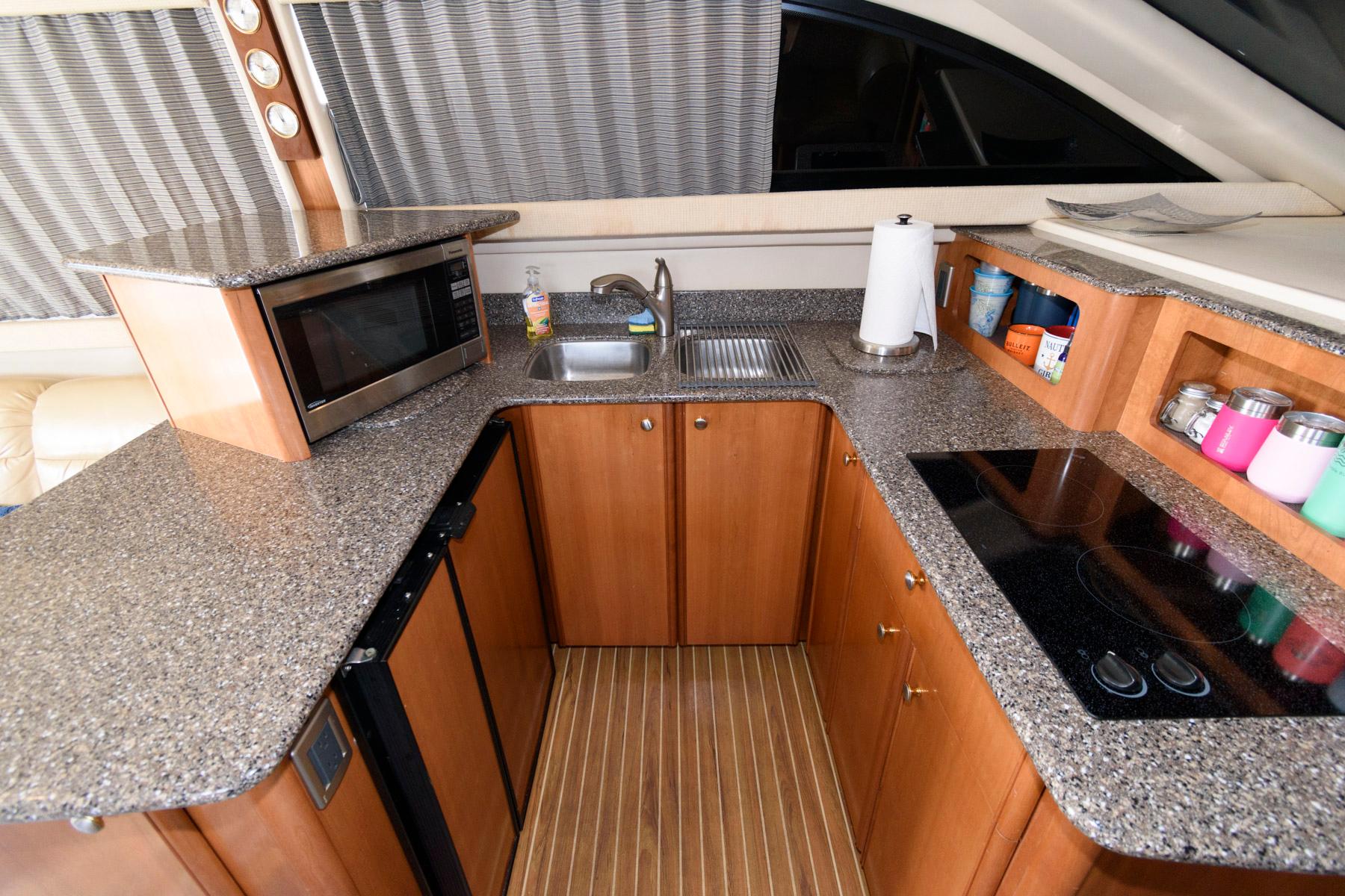 2004 Meridian 381 Sedan kitchen with granite countertops, microwave, sink, and electric stove.