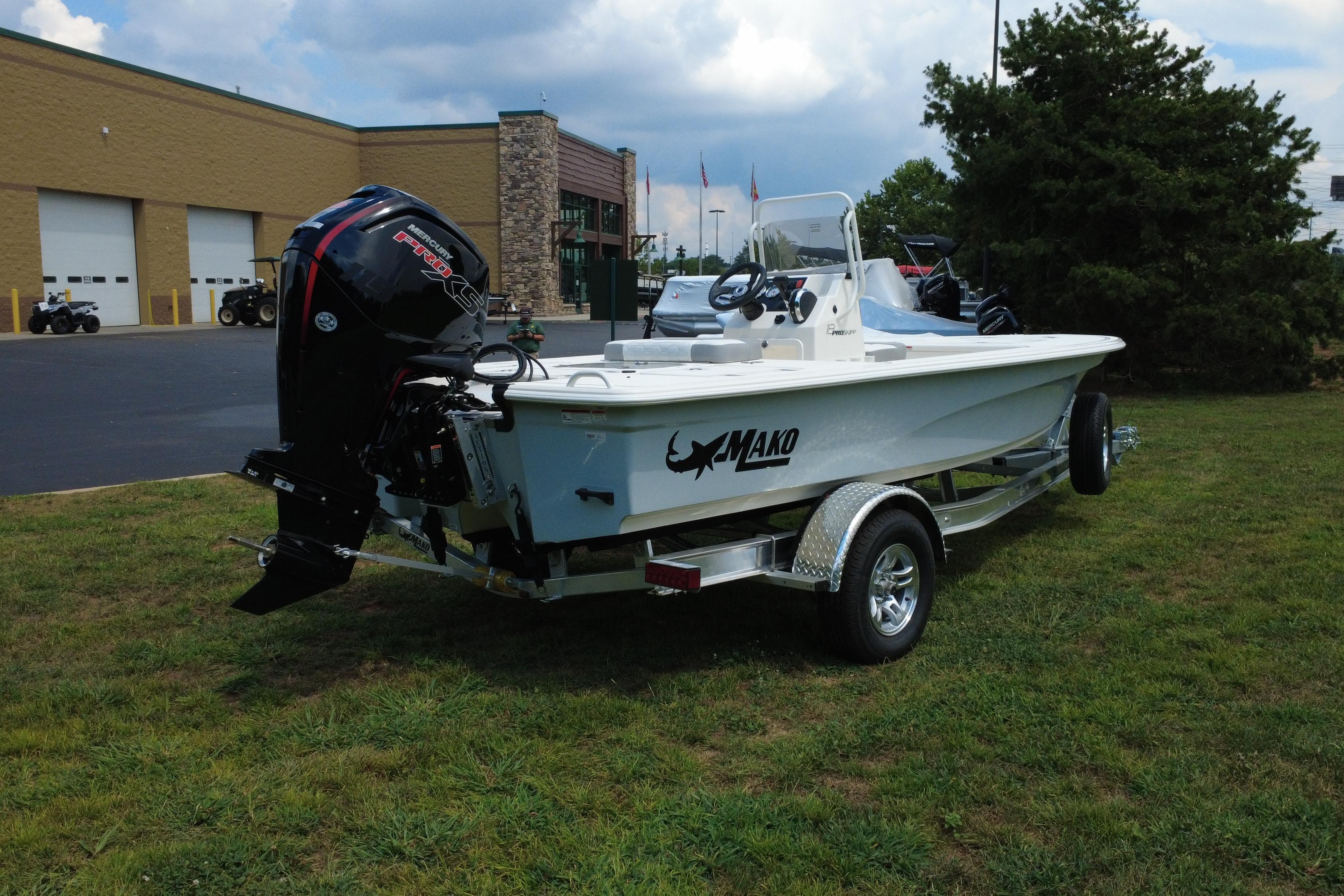 2026 Mako 18 Pro Skiff boat on trailer, parked on grass near a building.