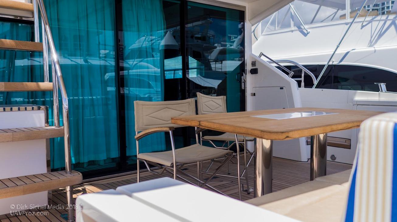 Outdoor seating area on 2012 Fairline Squadron 65 yacht with wooden table and chairs.