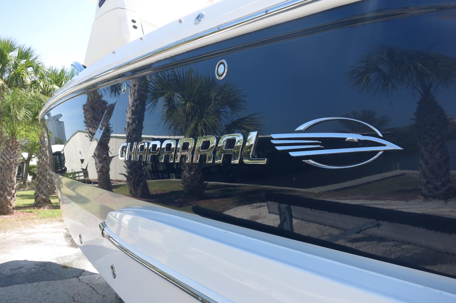2025 Chaparral 270 OSX boat with logo, reflecting palm trees.