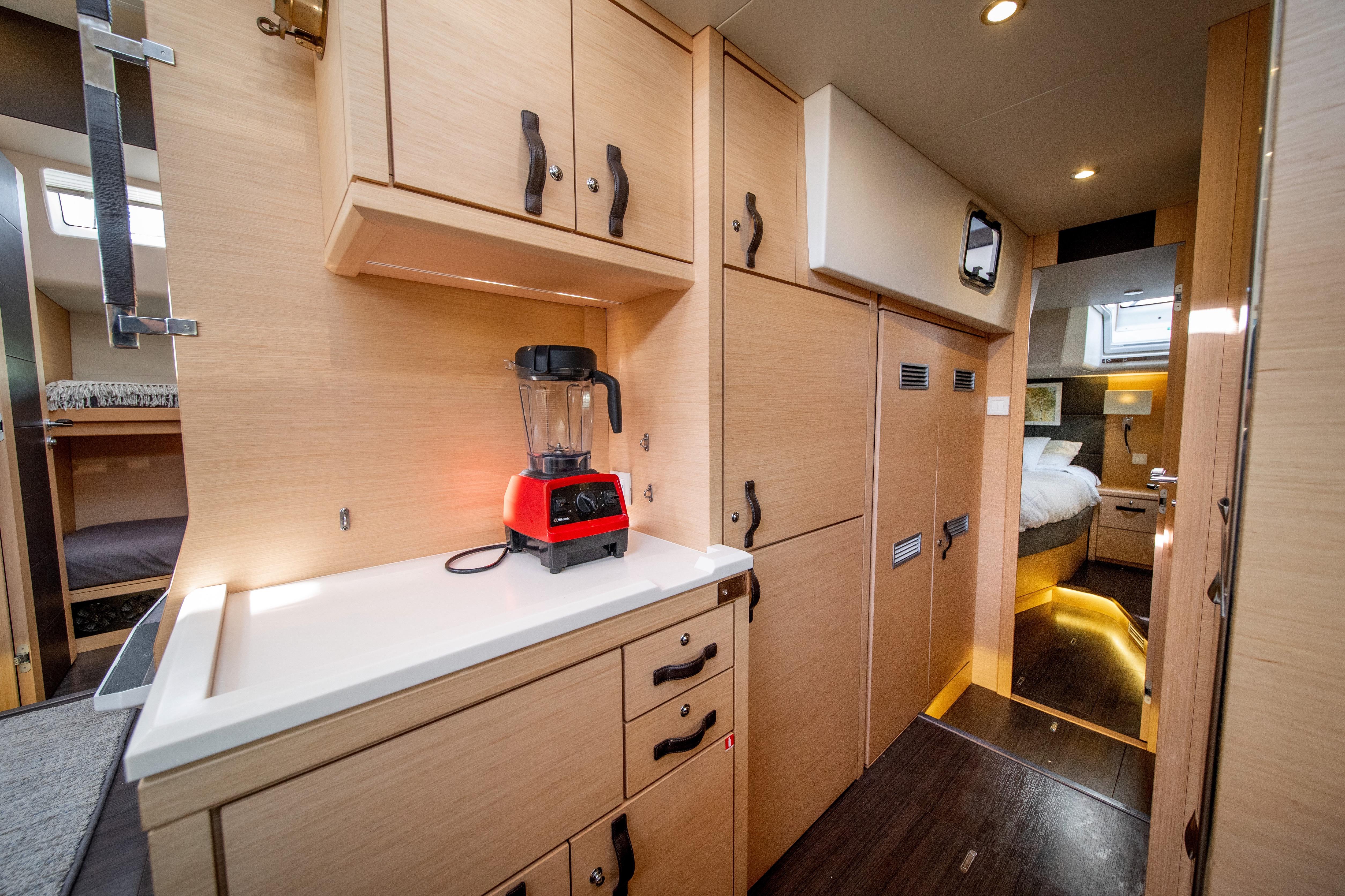 Luxurious interior of a 2016 Jeanneau 64 yacht featuring a modern kitchen and cozy bedroom.