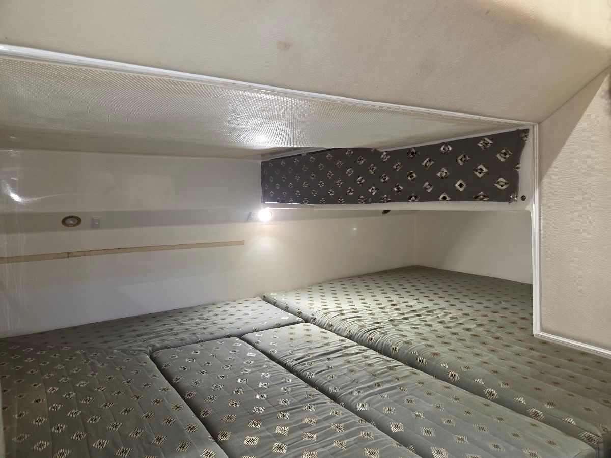 The interior shows a spacious sleeping cabin with cushioned mattresses and a small light.