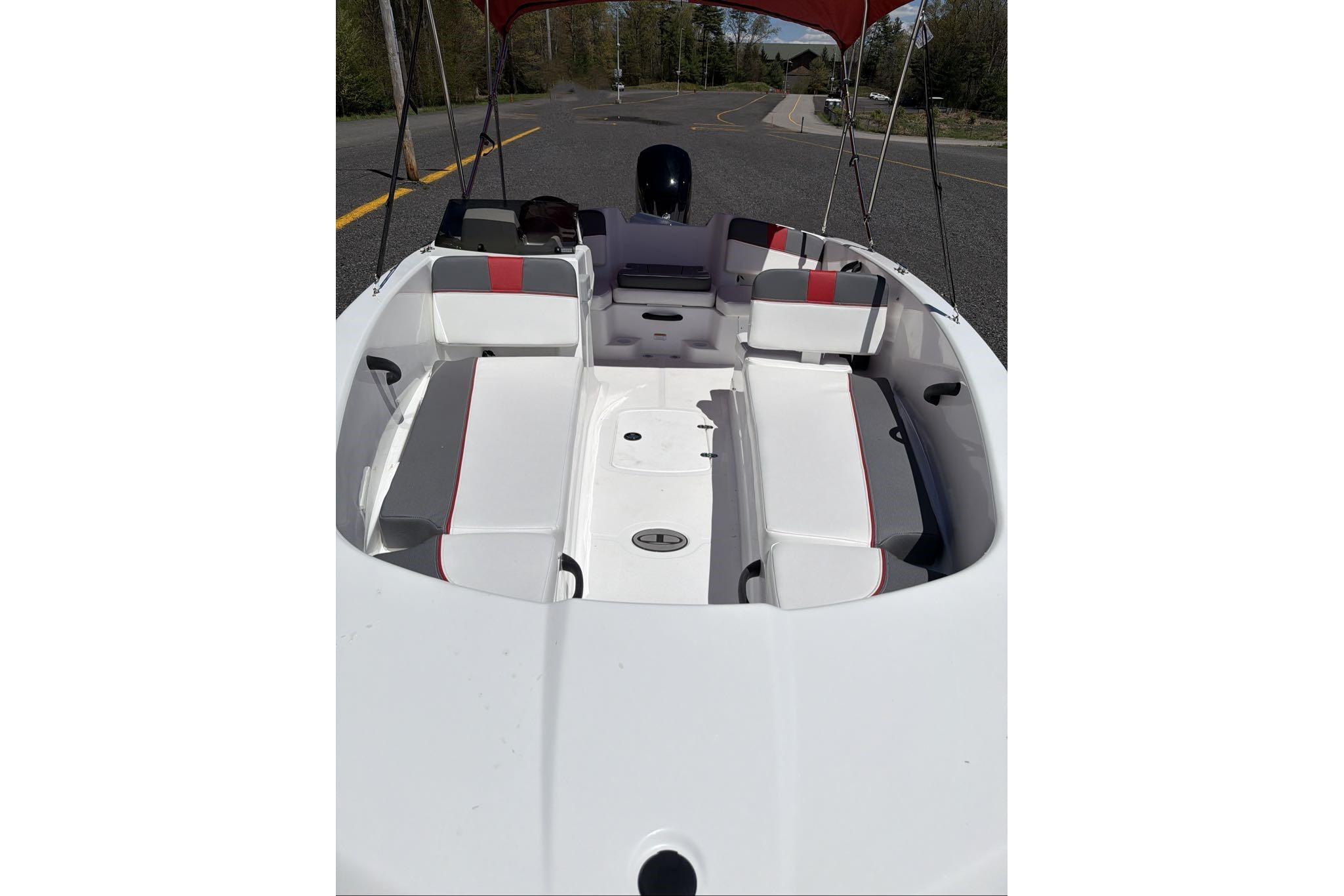 2026 Tahoe T18 boat interior with white and red seating, parked on a road.