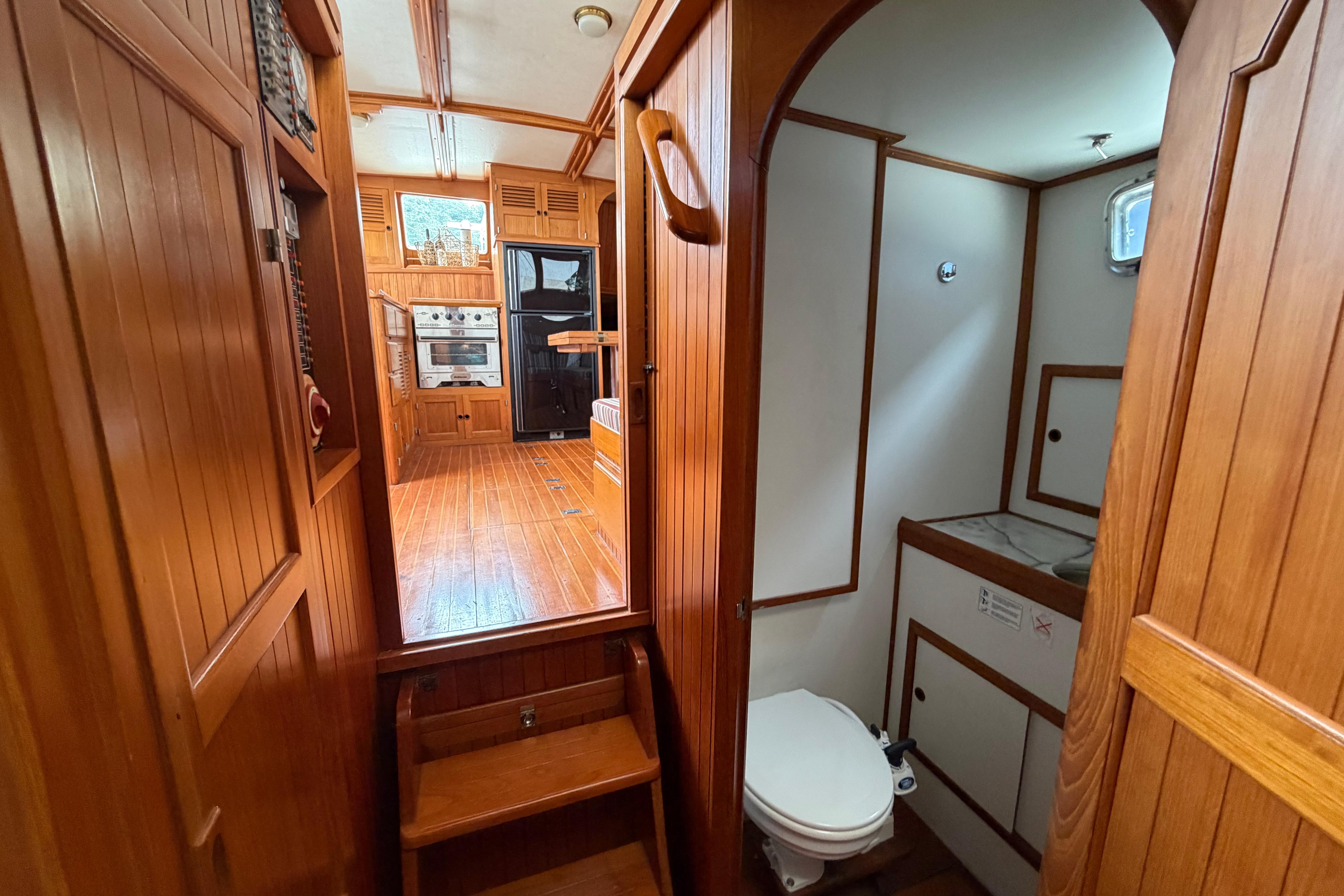 Interior of 1988 Monk 36 boat with wooden cabinetry and compact bathroom.
