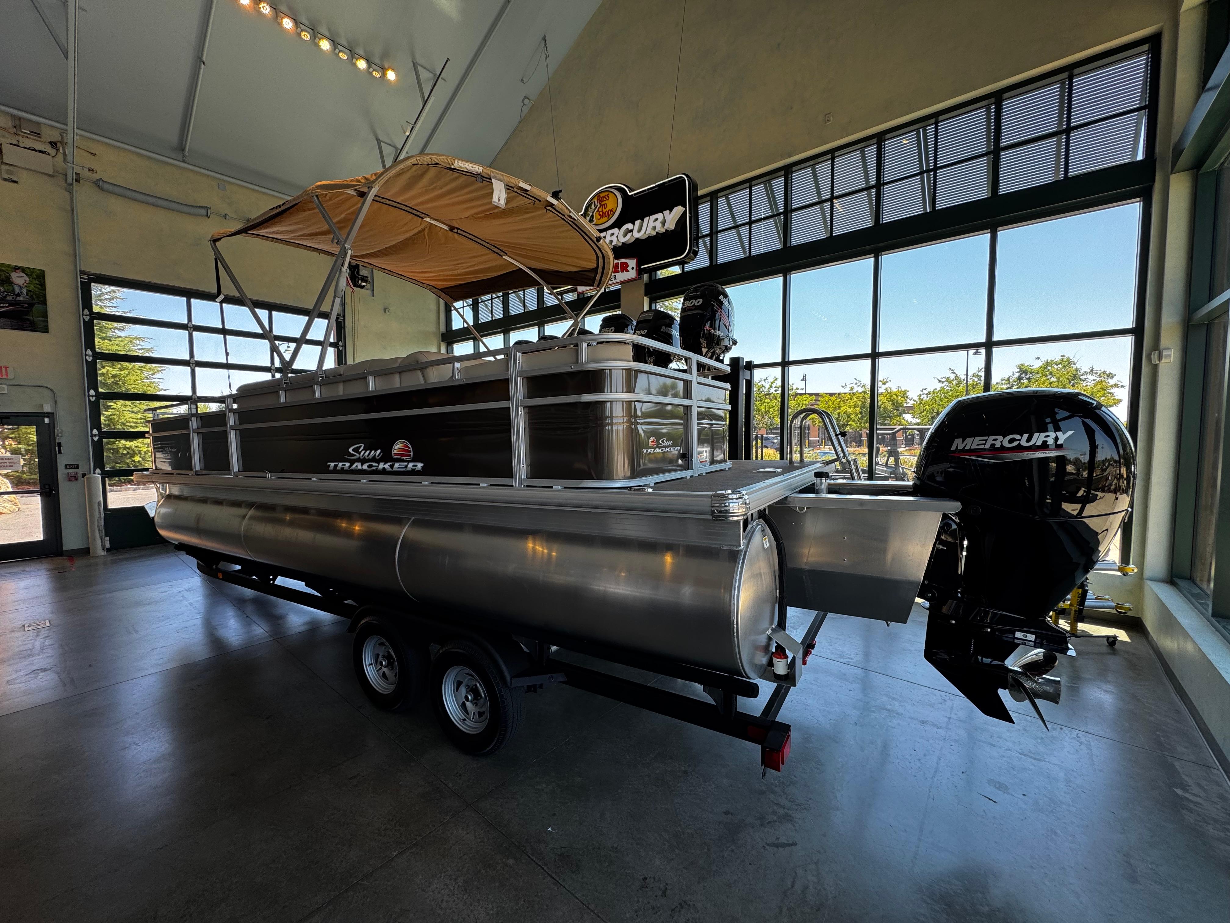 2025 Sun Tracker Sportfish 24 XP3 pontoon boat with Mercury engine in showroom.