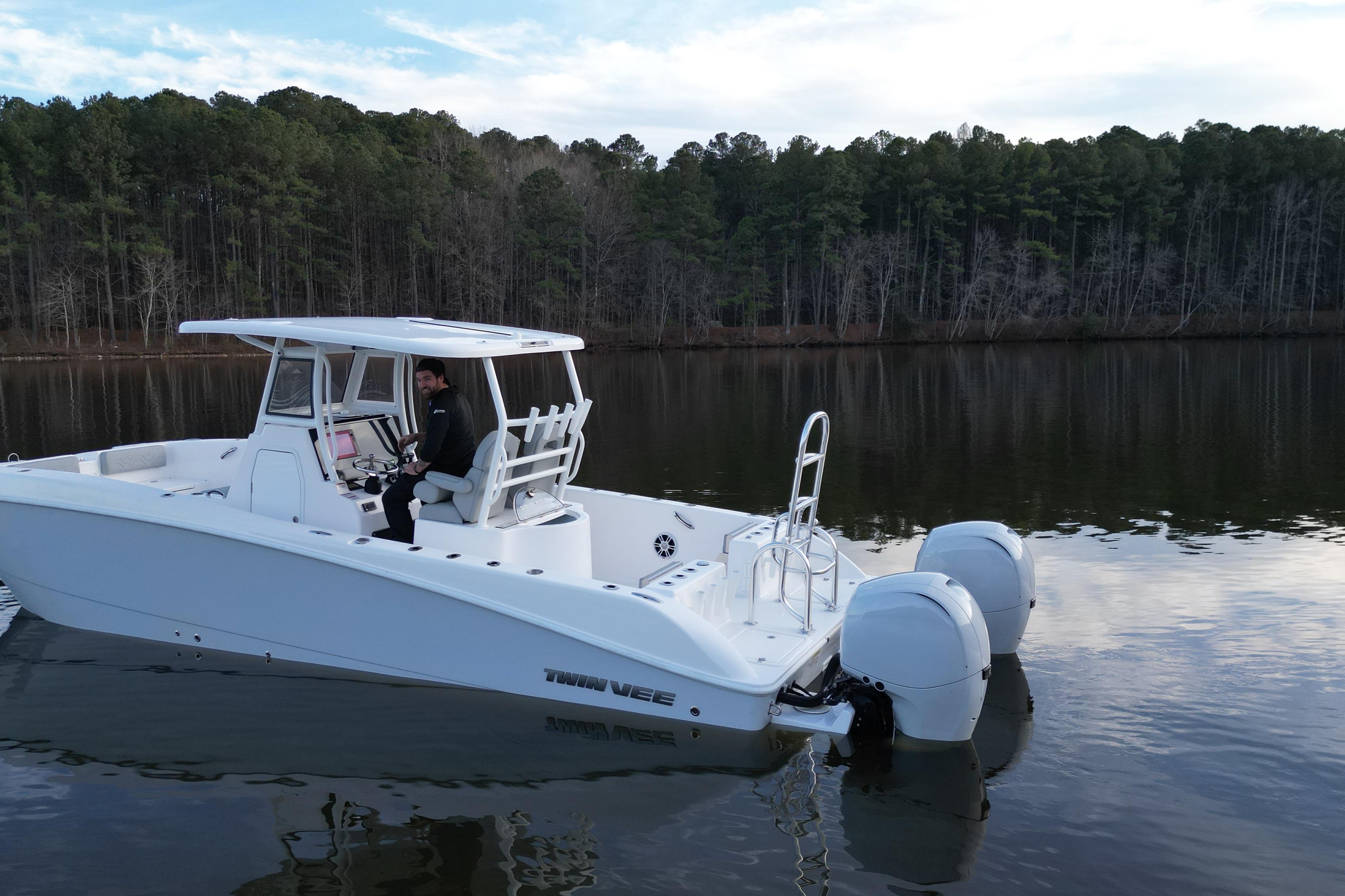 2023 Twin Vee 260 GFX CC boat on calm lake with forest backdrop.