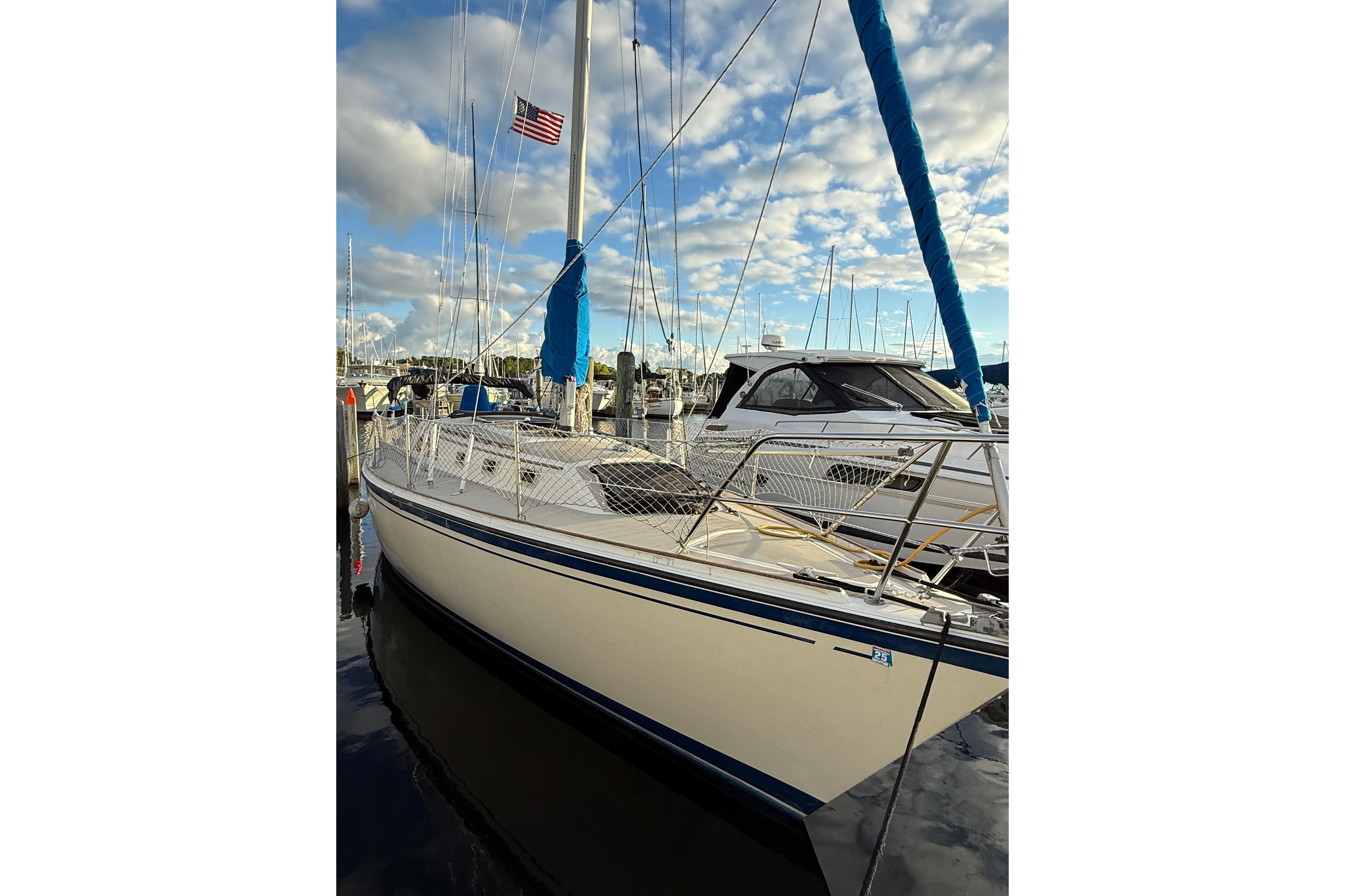 1983 O'Day 34 sailboat docked, featuring blue accents and an American flag.