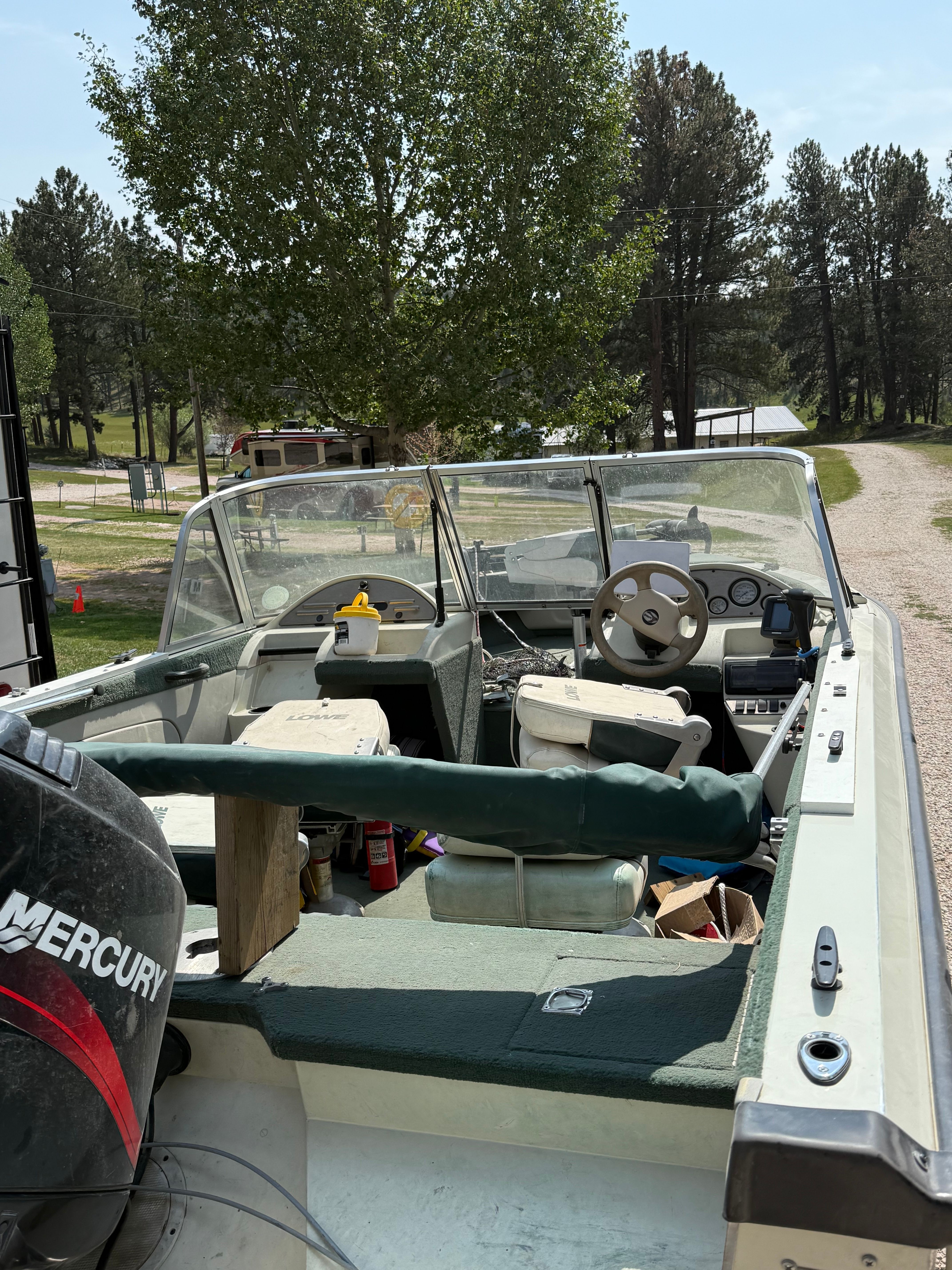 1999 Lowe Roughneck boat with Mercury engine parked outdoors.