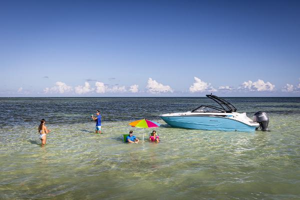 2025 Hurricane SunDeck 235 OB boat anchored near beach with people enjoying the water.
