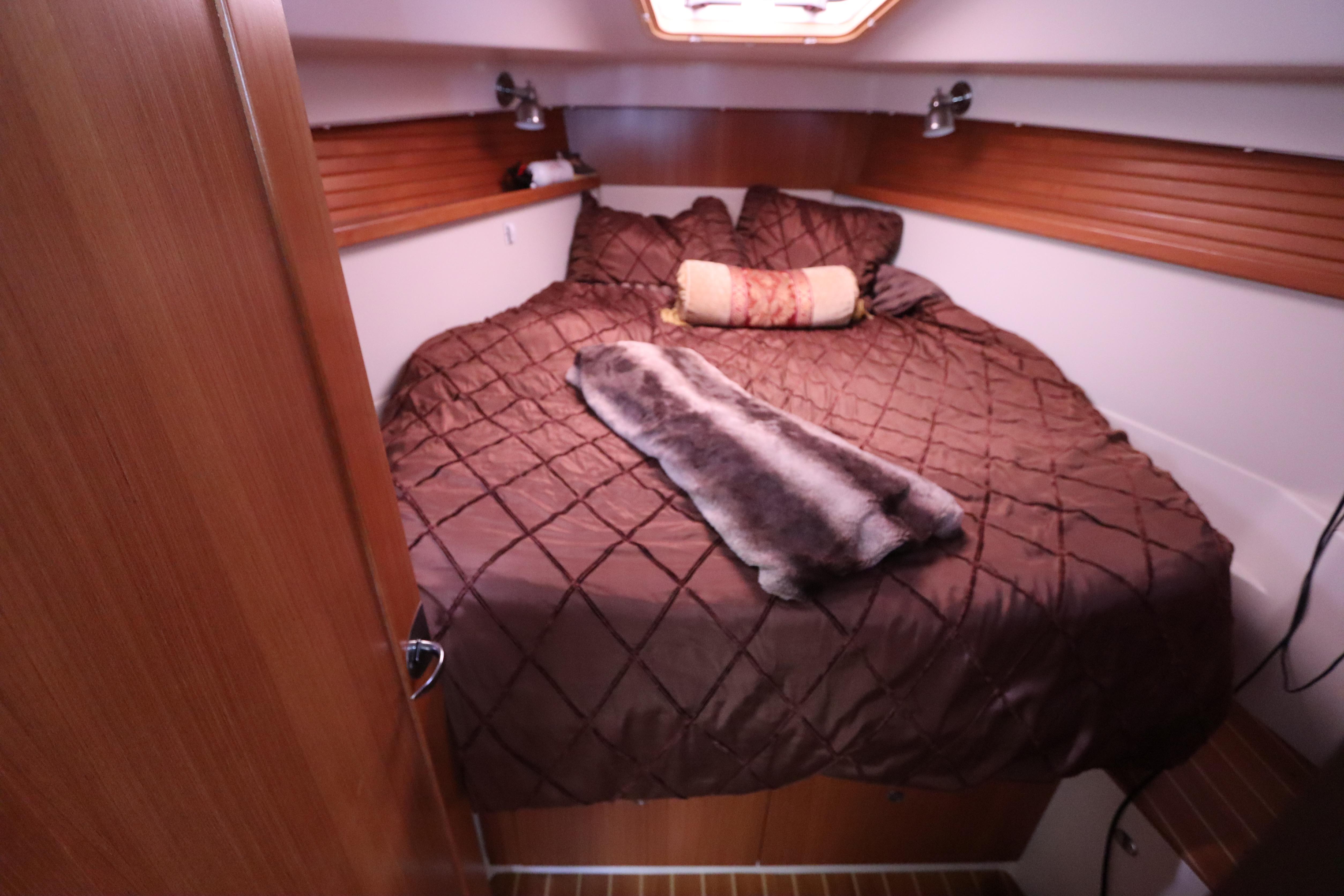 Cozy cabin interior of 2011 Catalina 355 sailboat with plush bedding and wood accents.
