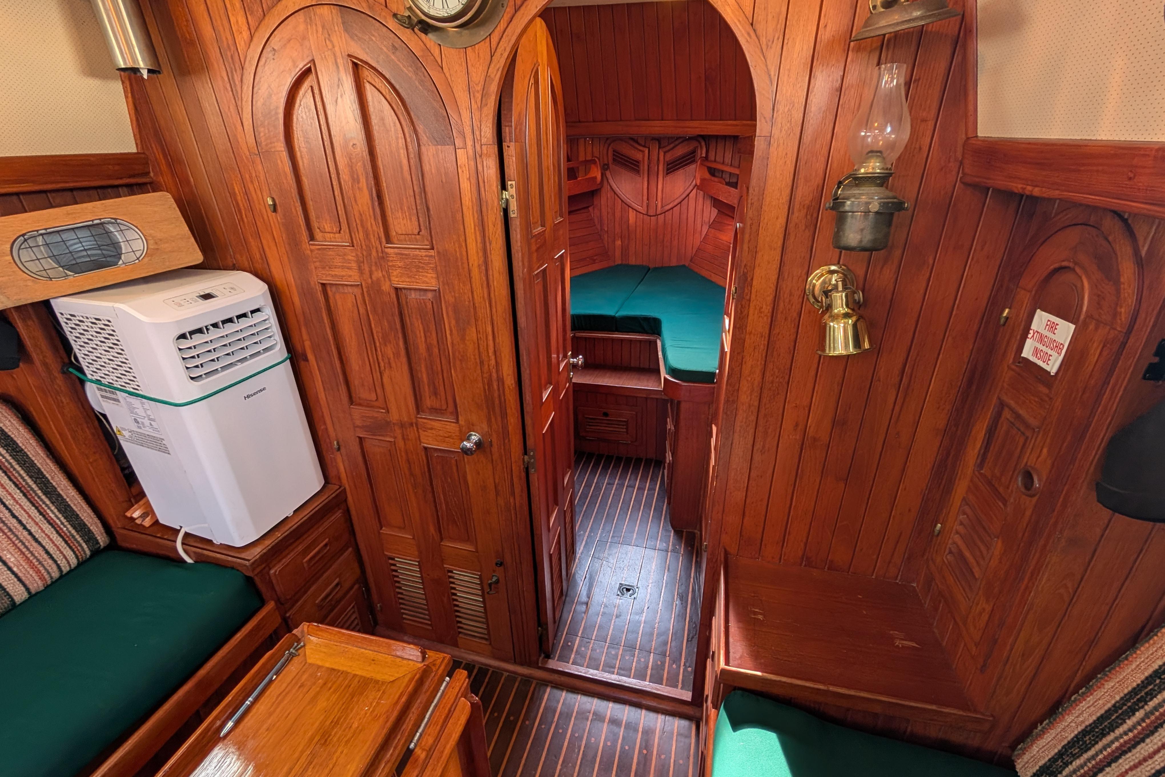 Cozy 1983 Robert Perry 41 yacht interior with wood paneling and green cushions.