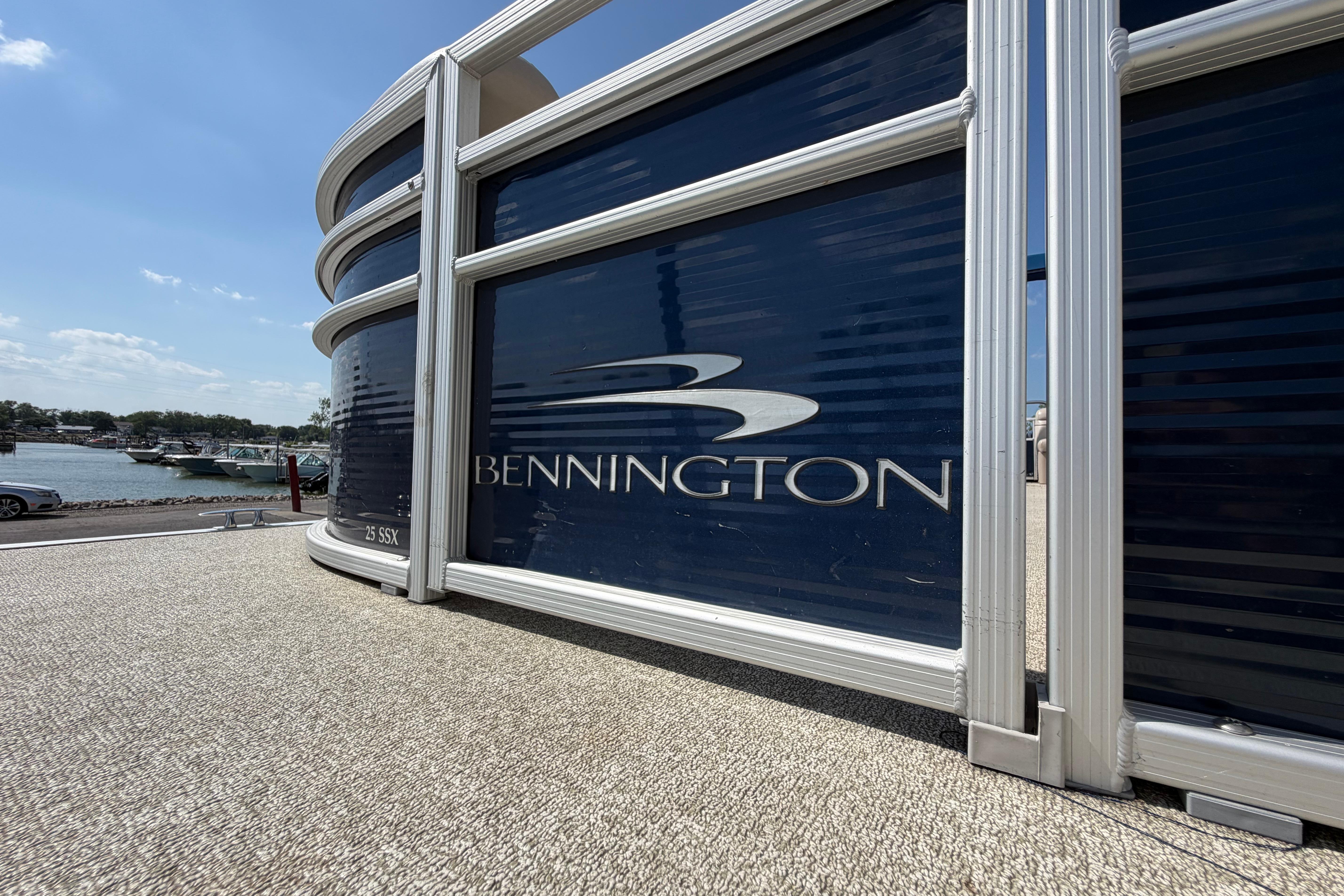 2017 Bennington 25 SSXAPG pontoon boat docked by a scenic waterfront.