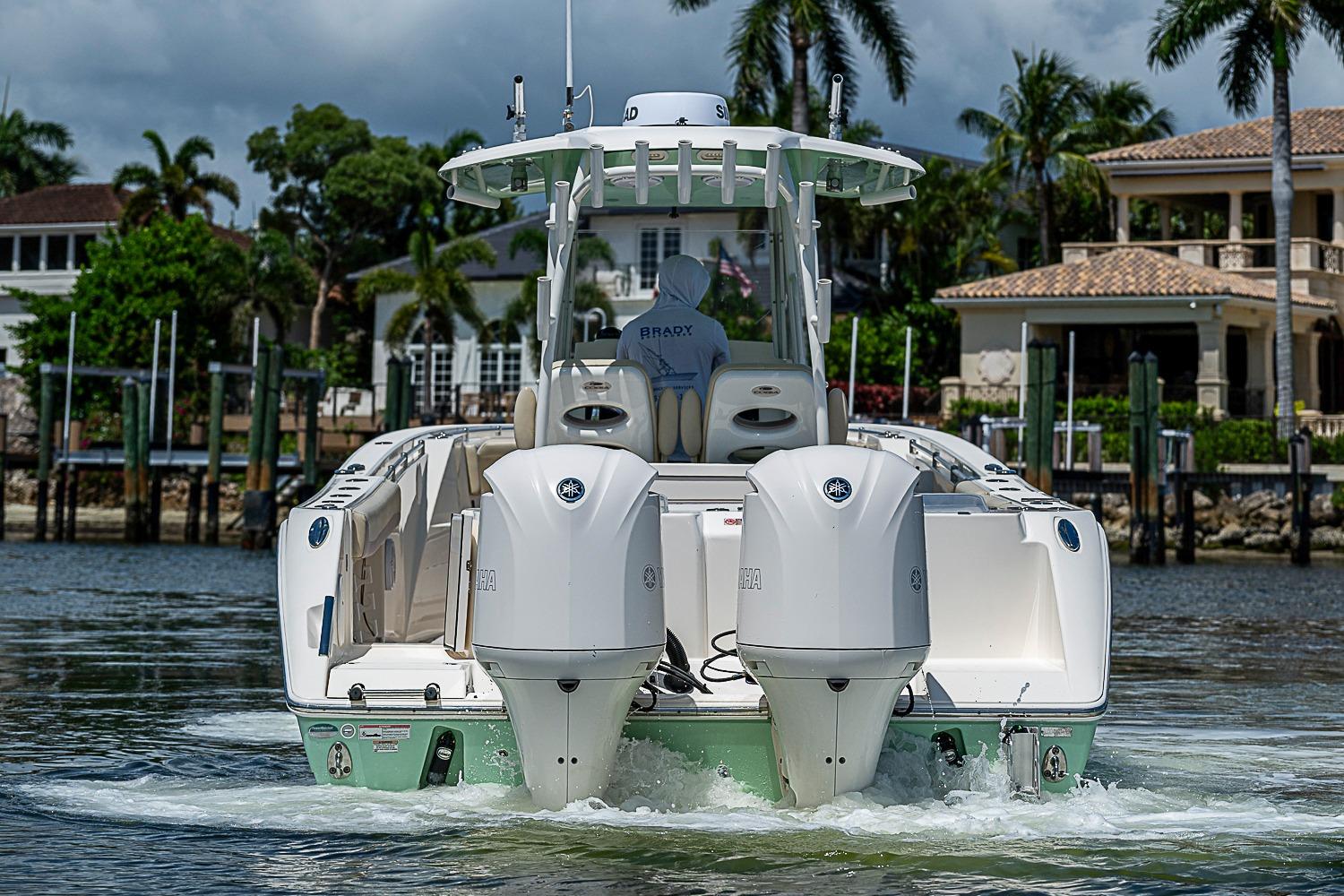 2019 Cobia 320 Center Console boat cruising near waterfront homes.