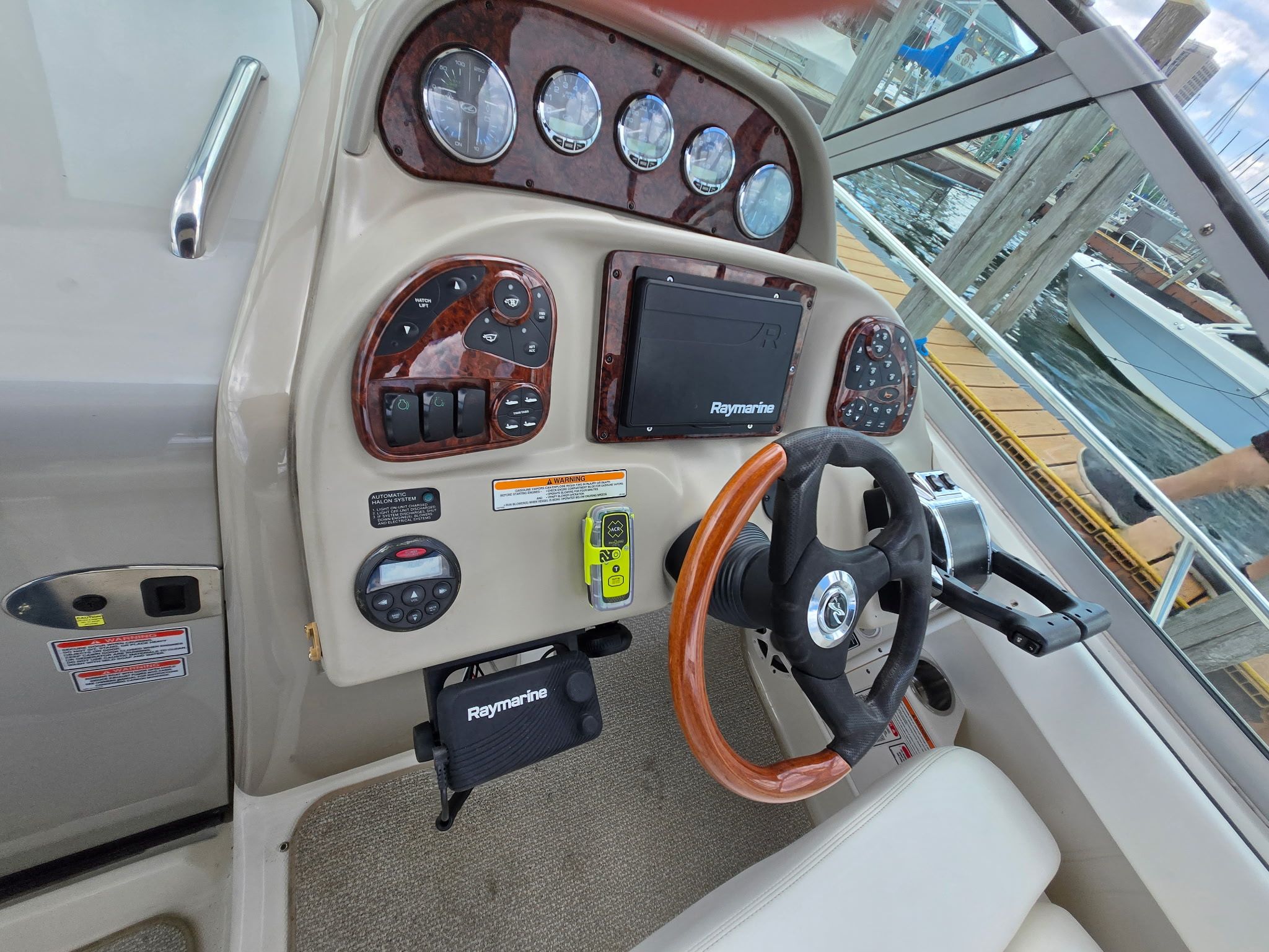 The cockpit of a 2006 Sea Ray 300 Sundancer with a wood steering wheel and navigation system.