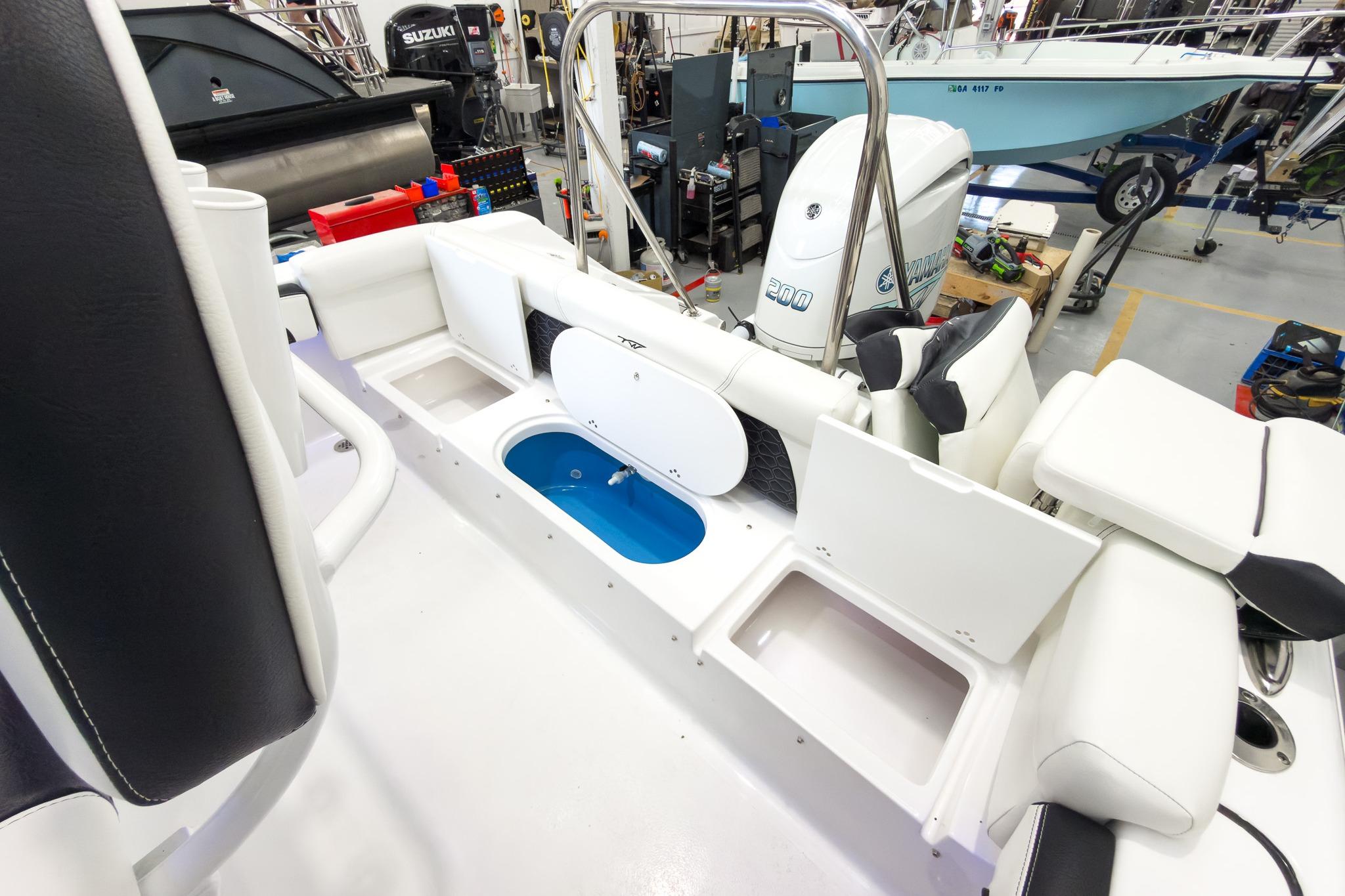 The image shows the cockpit of a Tidewater 220 LXF boat with storage compartments and a blue container.