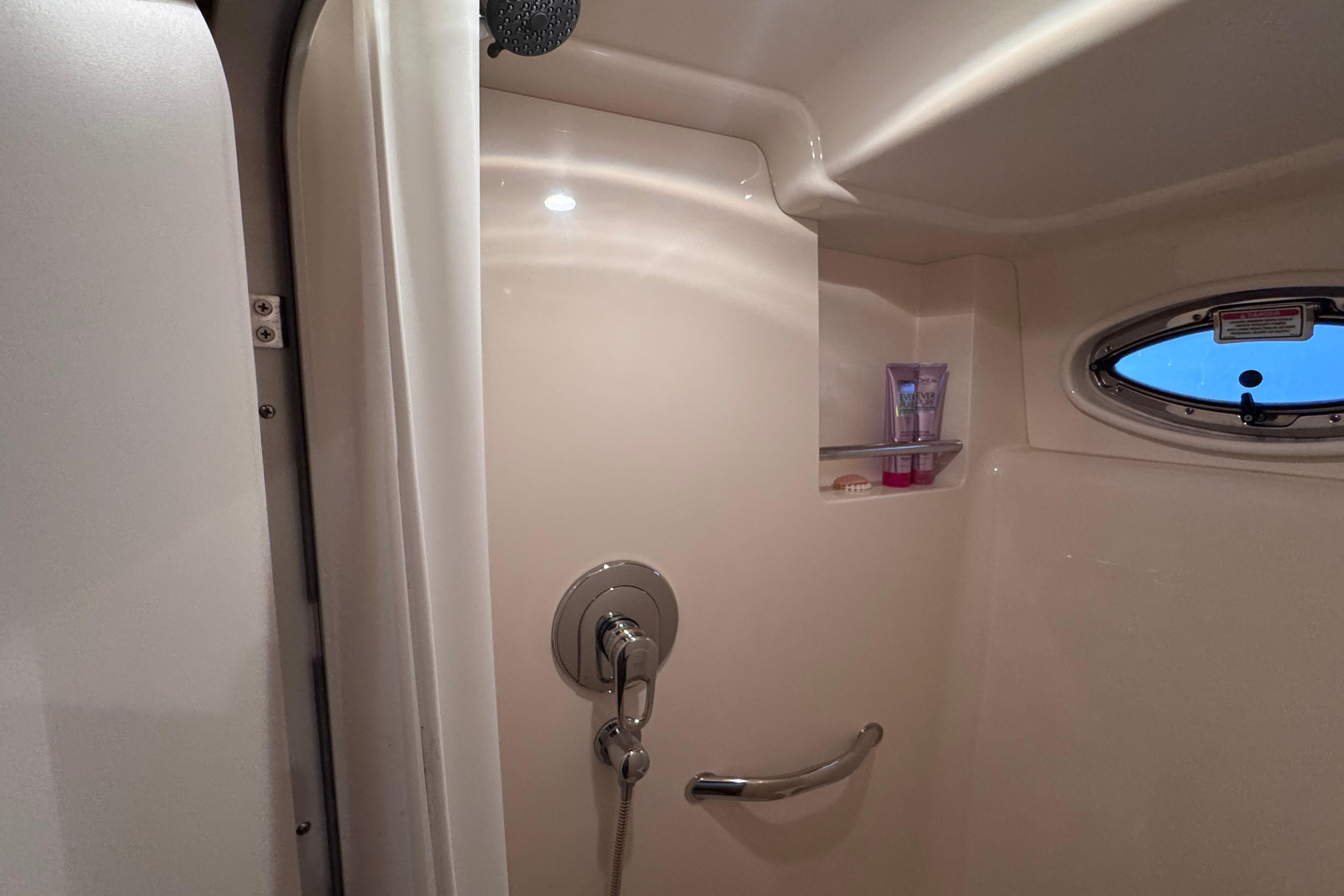 Shower area in 2004 Sea Ray 390 Motor Yacht with porthole and toiletries.