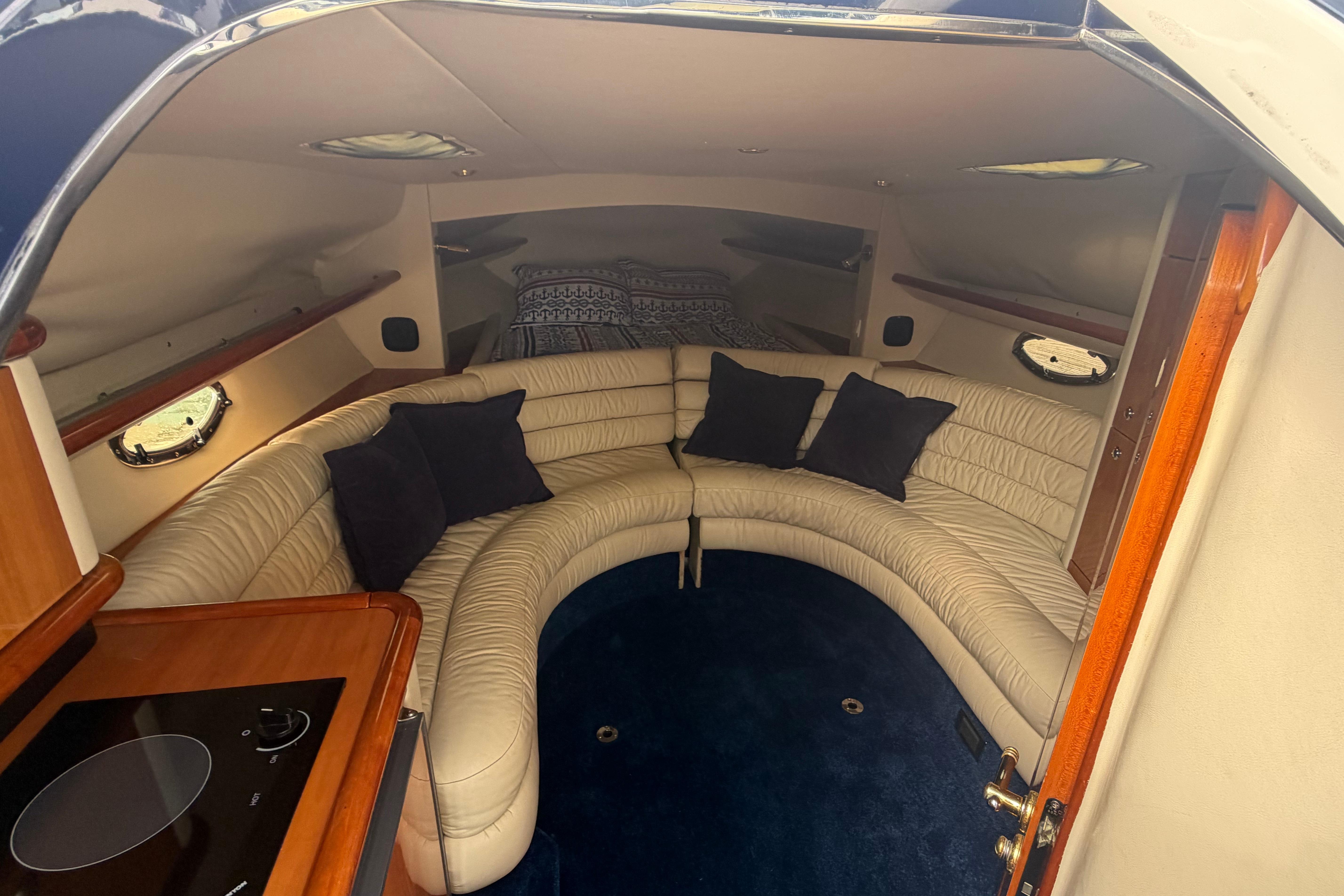 Luxurious interior of 2000 Sunseeker Superhawk 34 yacht with curved seating and cushions.