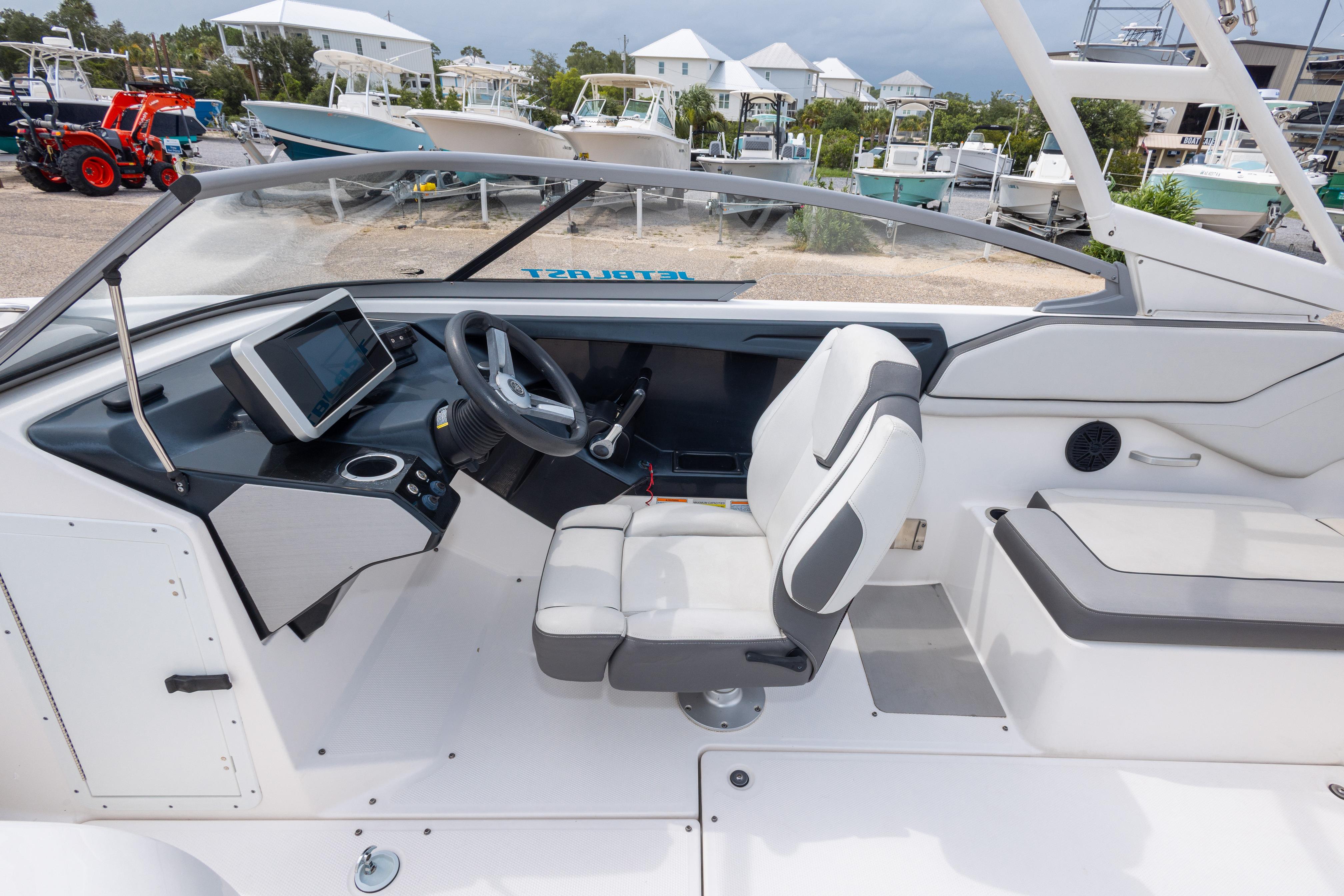 2021 Yamaha Boats AR250 interior with steering wheel, dashboard, and seating in a marina setting.