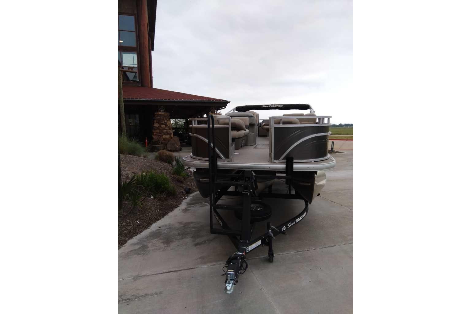 2025 Sun Tracker Fishin' Barge 22 XP3 pontoon boat on trailer, parked outdoors.