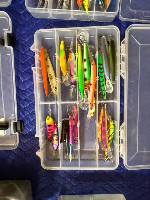 A fishing lure set in a transparent box with various colorful lures.