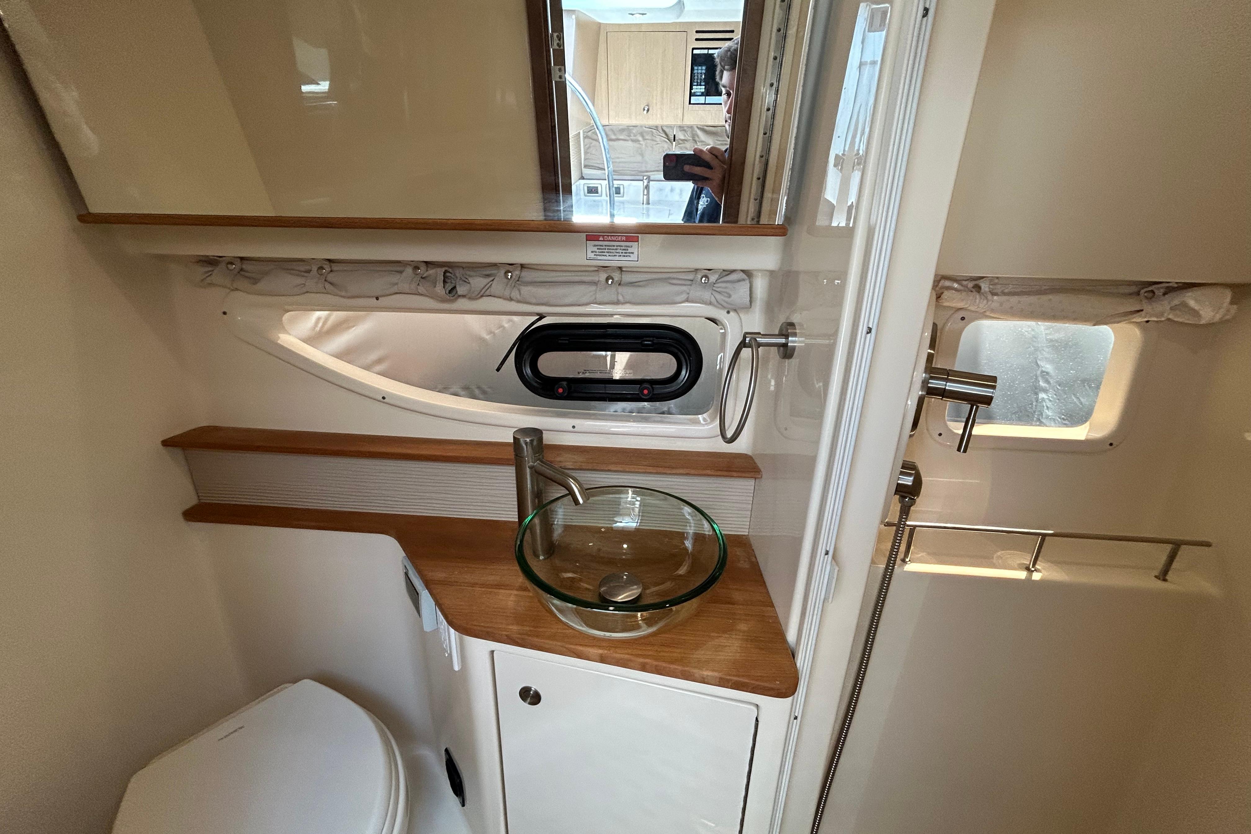 2019 Sea Ray Sundancer 350 bathroom with modern sink, wooden accents, and porthole window.