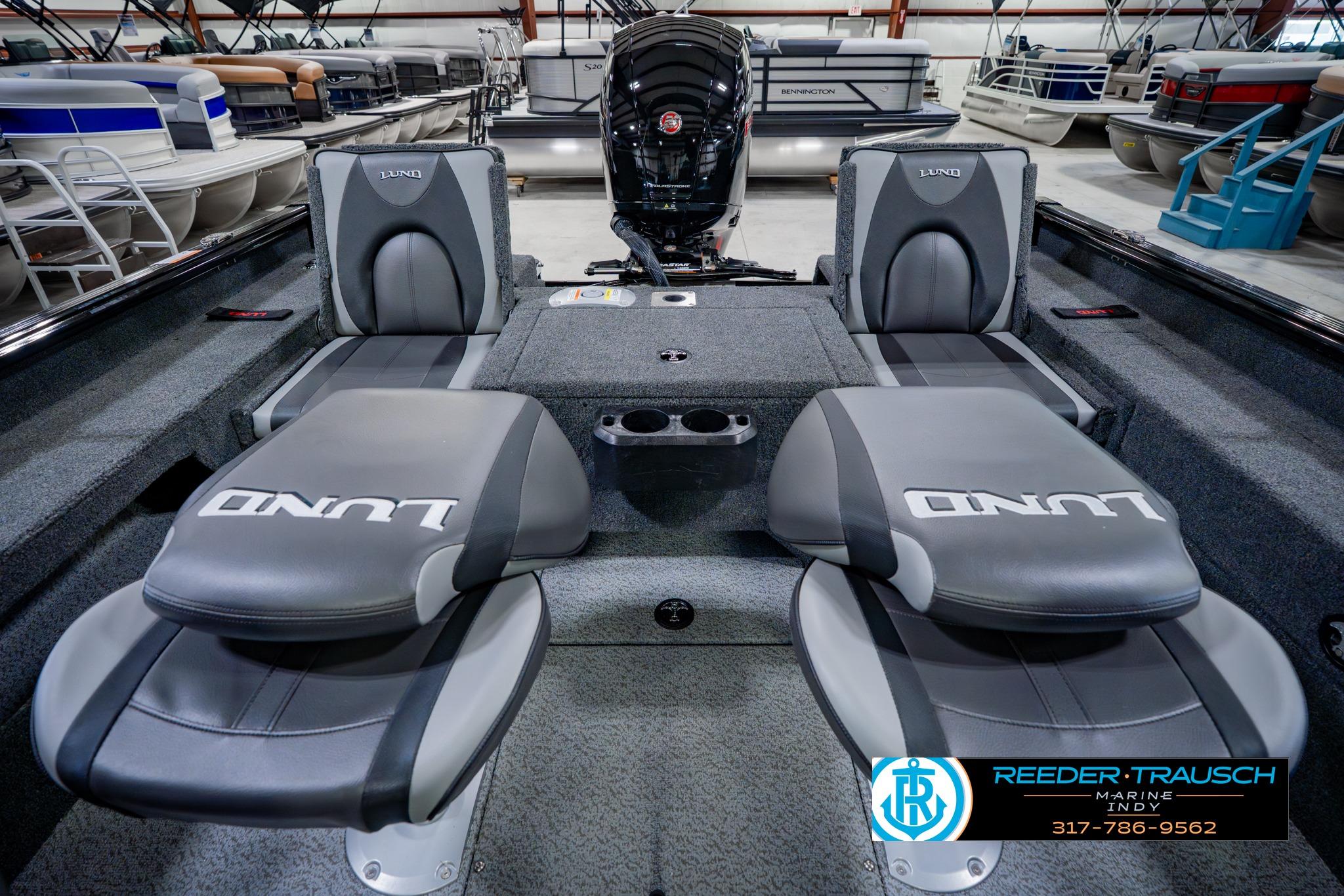 2026 Lund 1875 Impact XS boat interior with seating and motor, displayed in showroom.