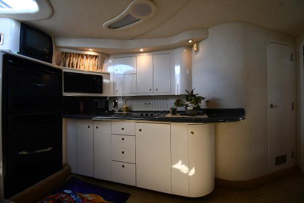 Interior of 1997 Sea Ray 400 Sundancer yacht kitchen with white cabinets and appliances.