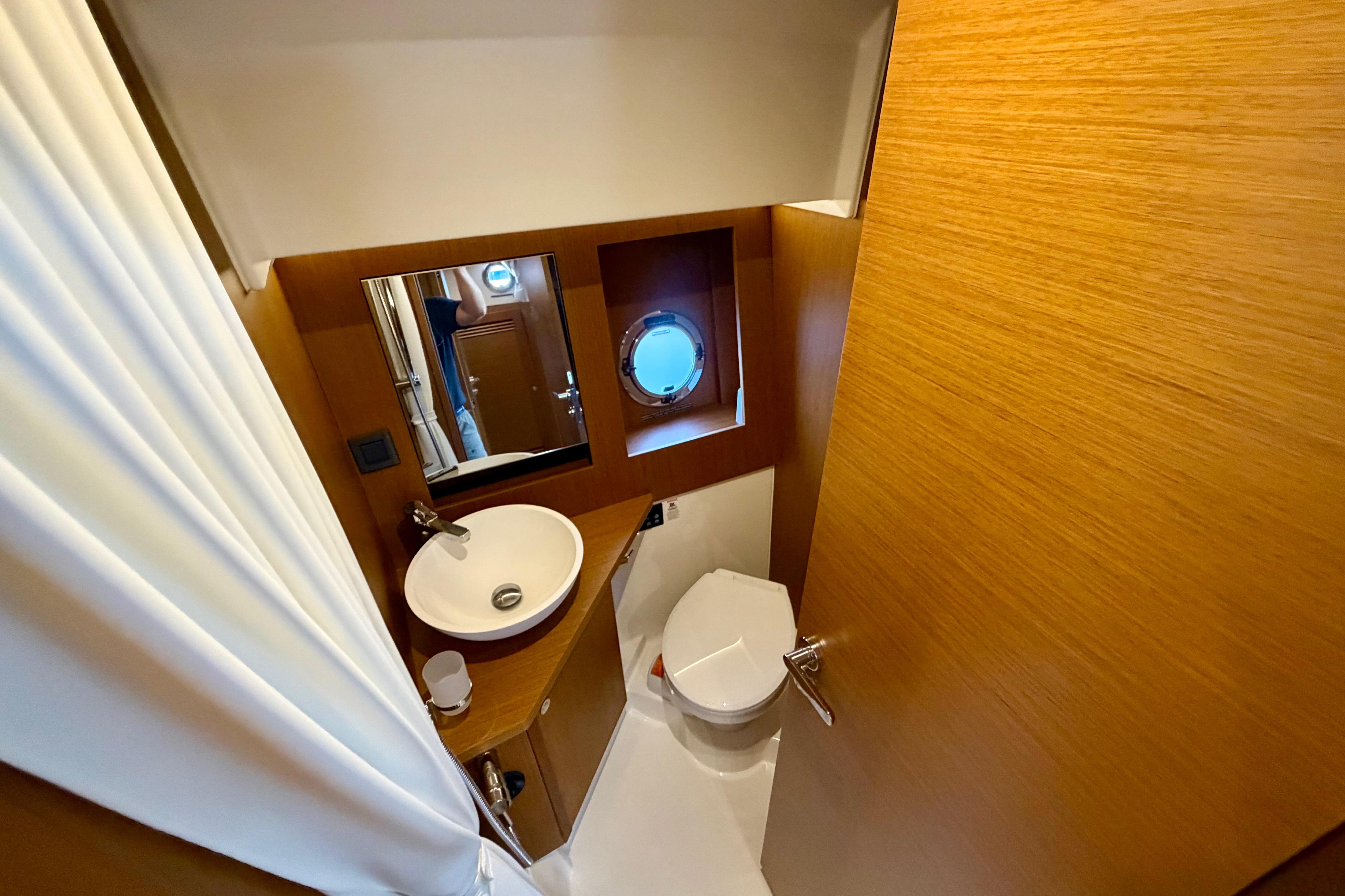 Bathroom interior of 2025 Beneteau Swift Trawler 41 Fly, featuring modern fixtures and porthole window.