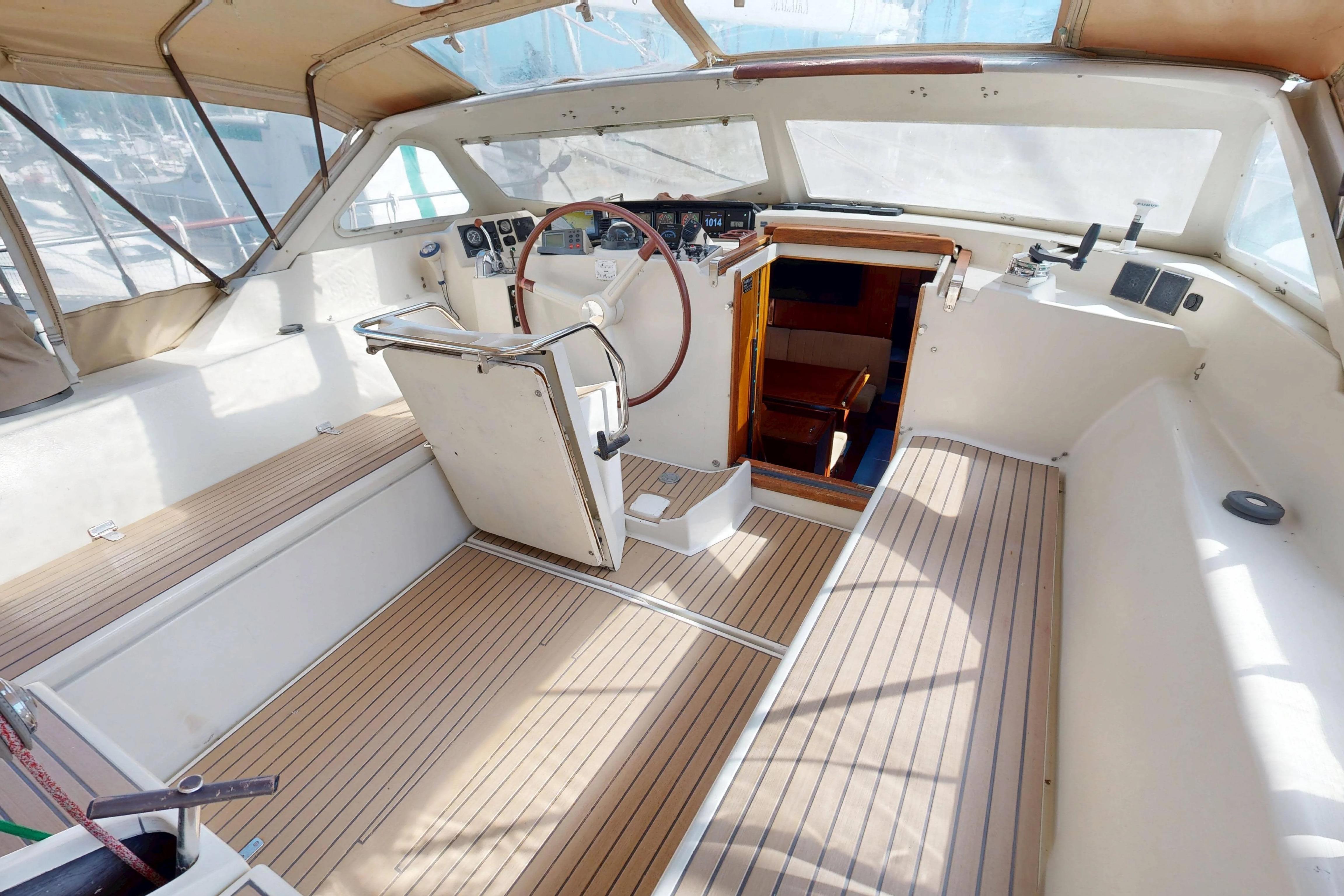 Cockpit of 1999 Amel Super Maramu 2000 sailboat with wooden flooring and steering wheel.