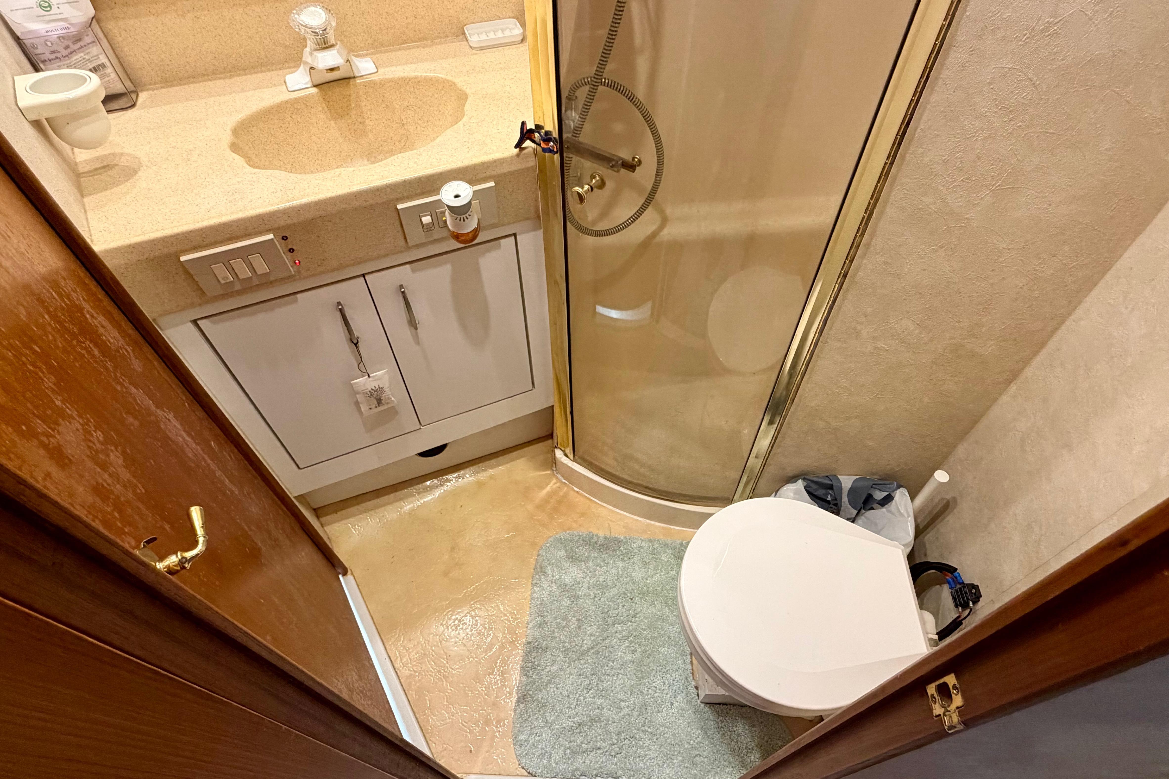 Compact bathroom in 1999 Ocean 40 Express yacht with shower, sink, and toilet.