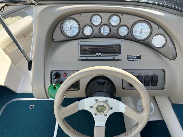 Dashboard of a 1995 Larson 174 SEI boat with gauges and steering wheel.
