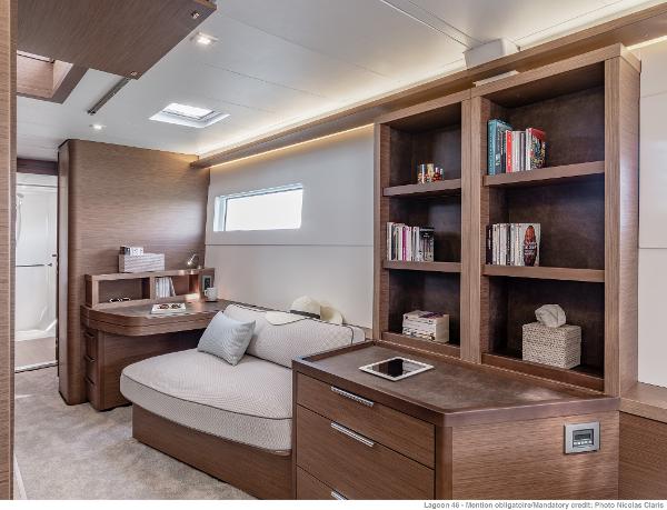 Luxurious interior of 2025 Lagoon 46 ICONIC yacht with modern furnishings and built-in bookshelves.