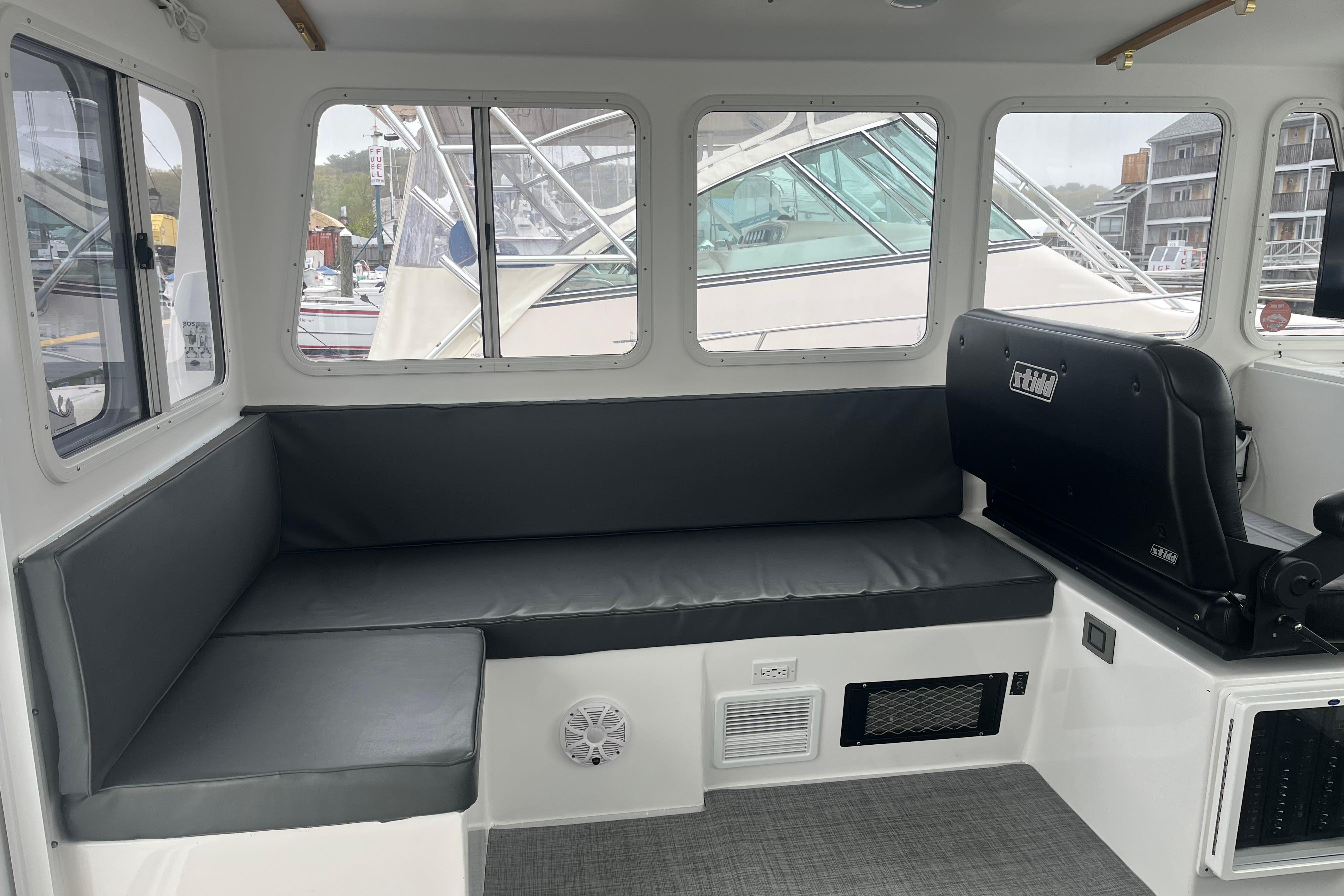 Interior of 2018 H&H Marine Osmond Beal boat with cushioned seating and large windows.