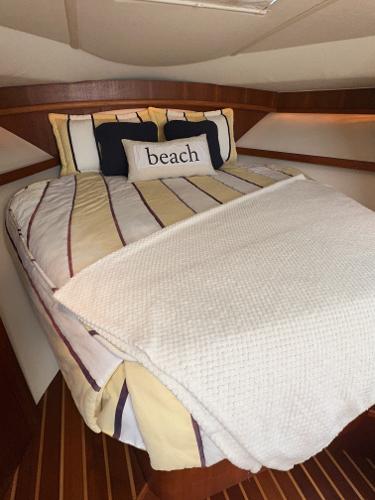 Cozy cabin interior of 2006 Tiara Yachts 3200 Open with striped bedding and "beach" pillow.
