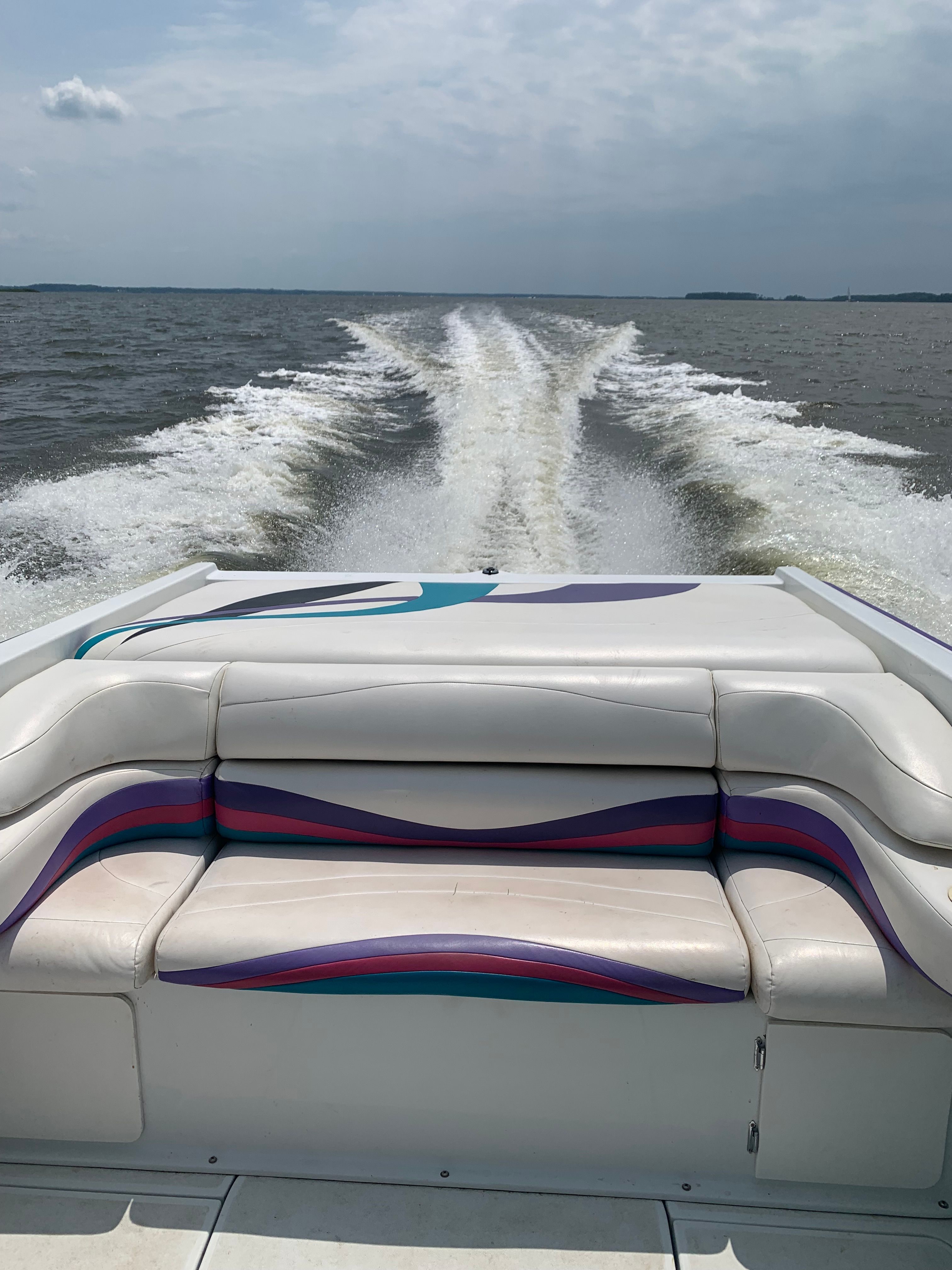 The image shows the stern of a boat with a white bench seat and colorful stripes.