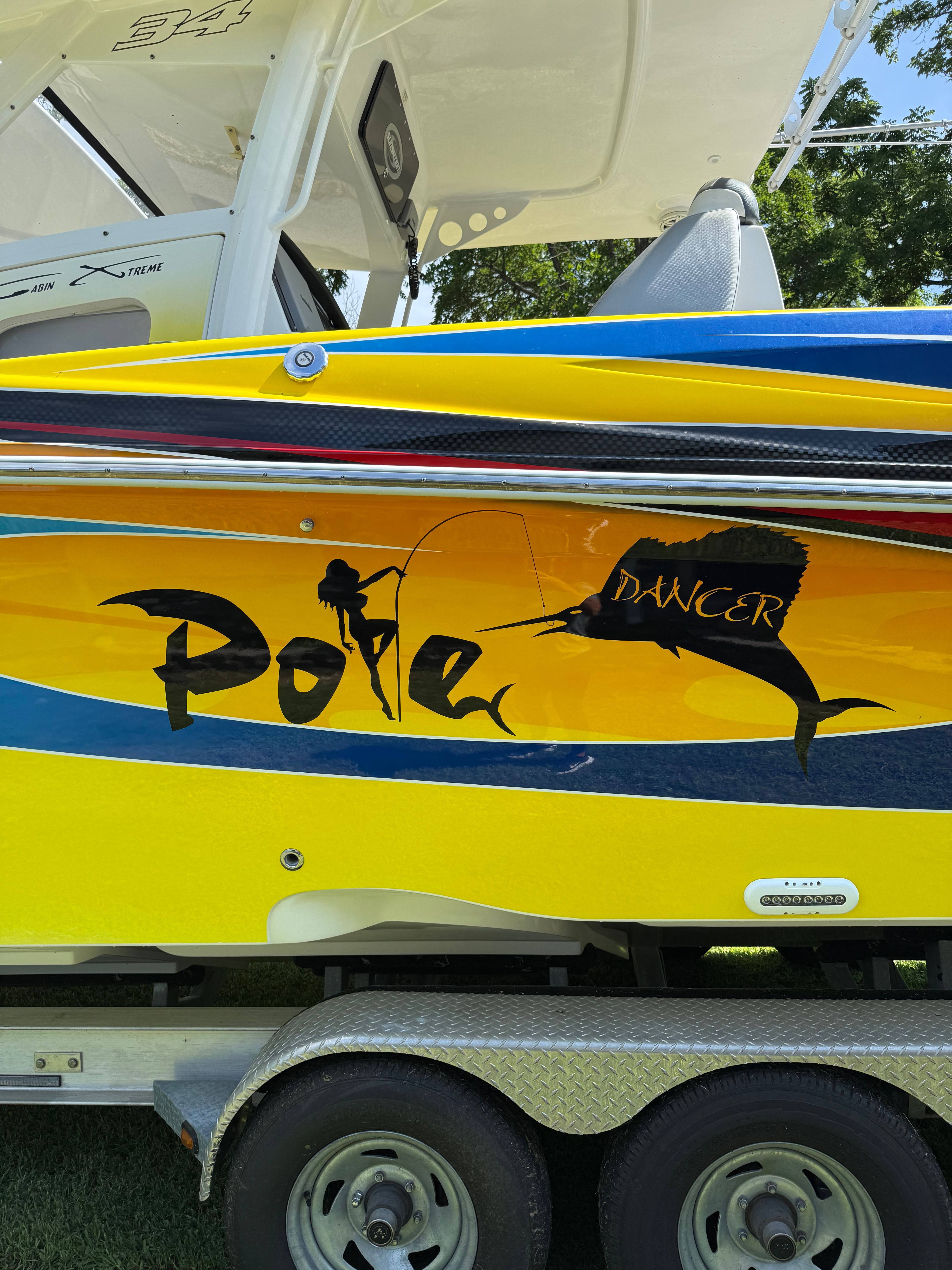 A yellow boat named "Pole Dancer" with a swordfish design on the side.