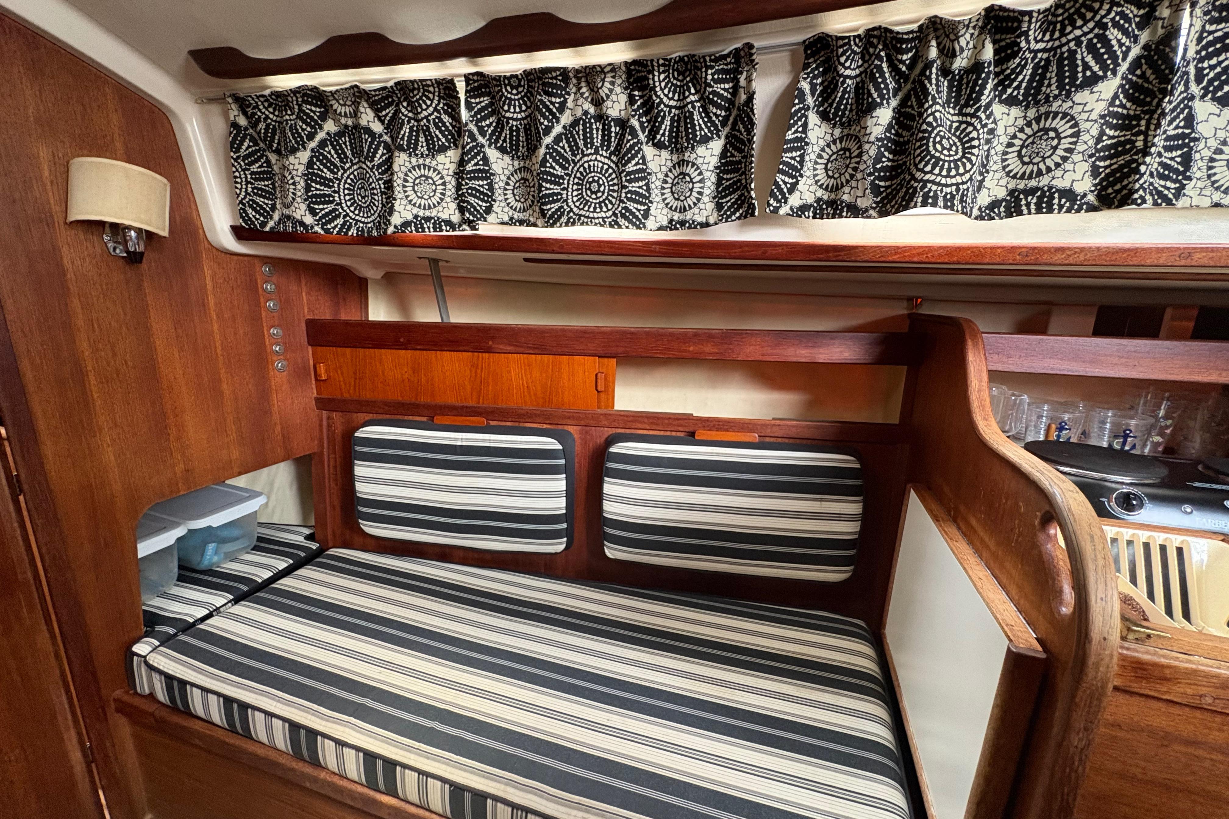 Interior of 1981 Sabre 31 sailboat with striped cushions and patterned curtains.
