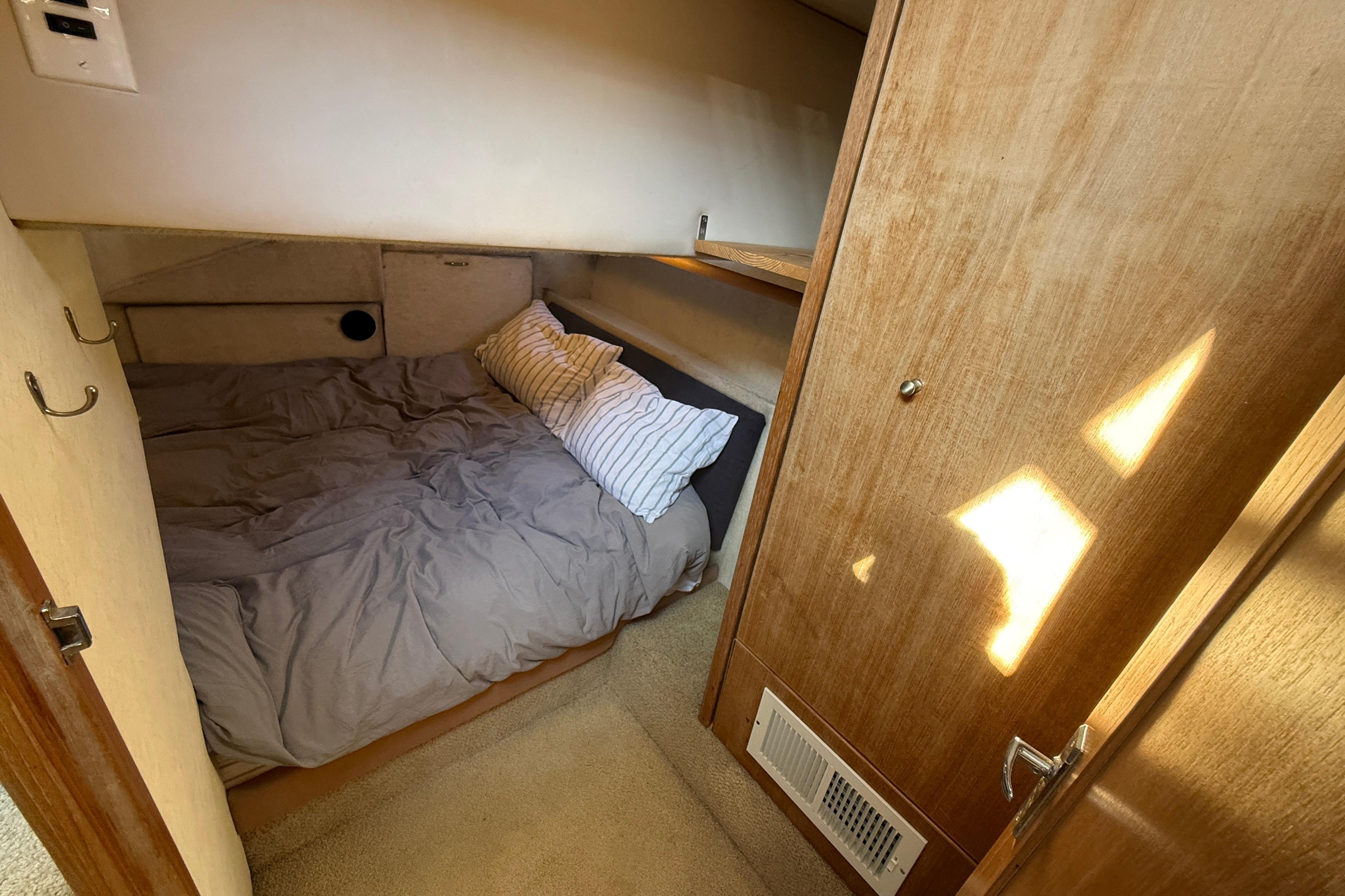 Cozy cabin interior of 1997 Bayliner 3988 Command Bridge Motoryacht with bed and wooden accents.