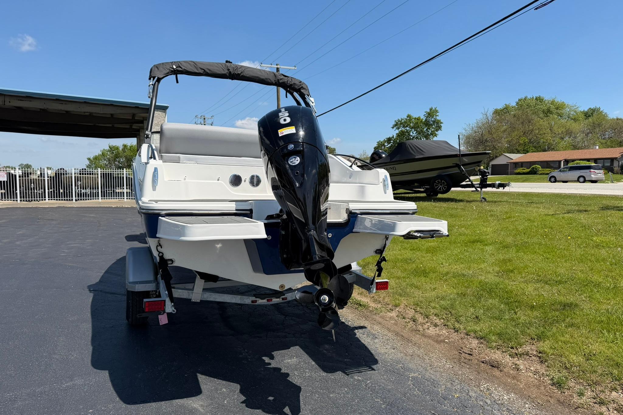 2026 Bayliner D20 boat with outboard motor on a trailer, parked outdoors.