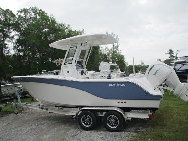 2025 Sea Fox 228 Commander boat on trailer, white and blue design, parked outdoors.