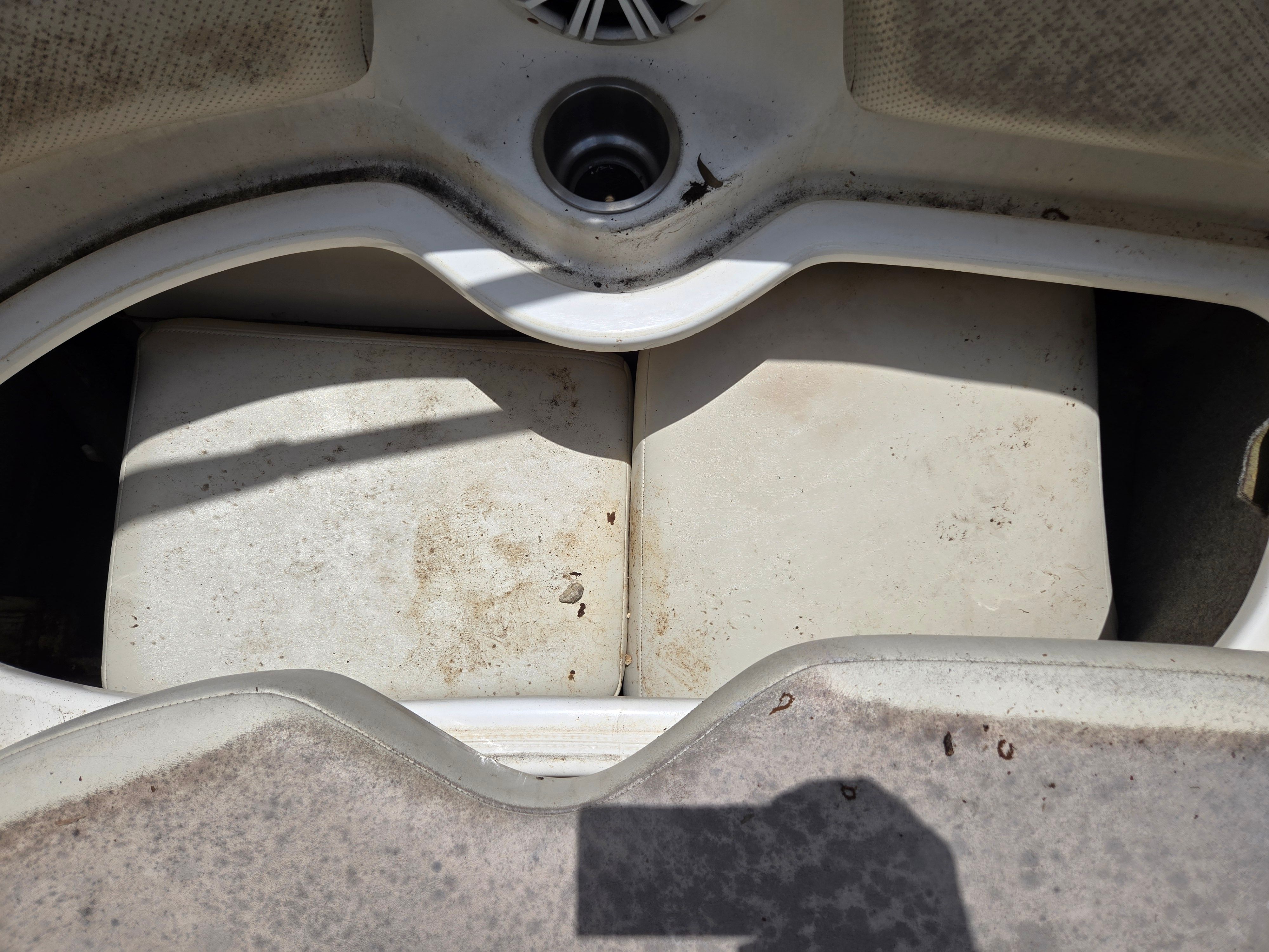 Close-up of a boat's seating area with worn cushions.