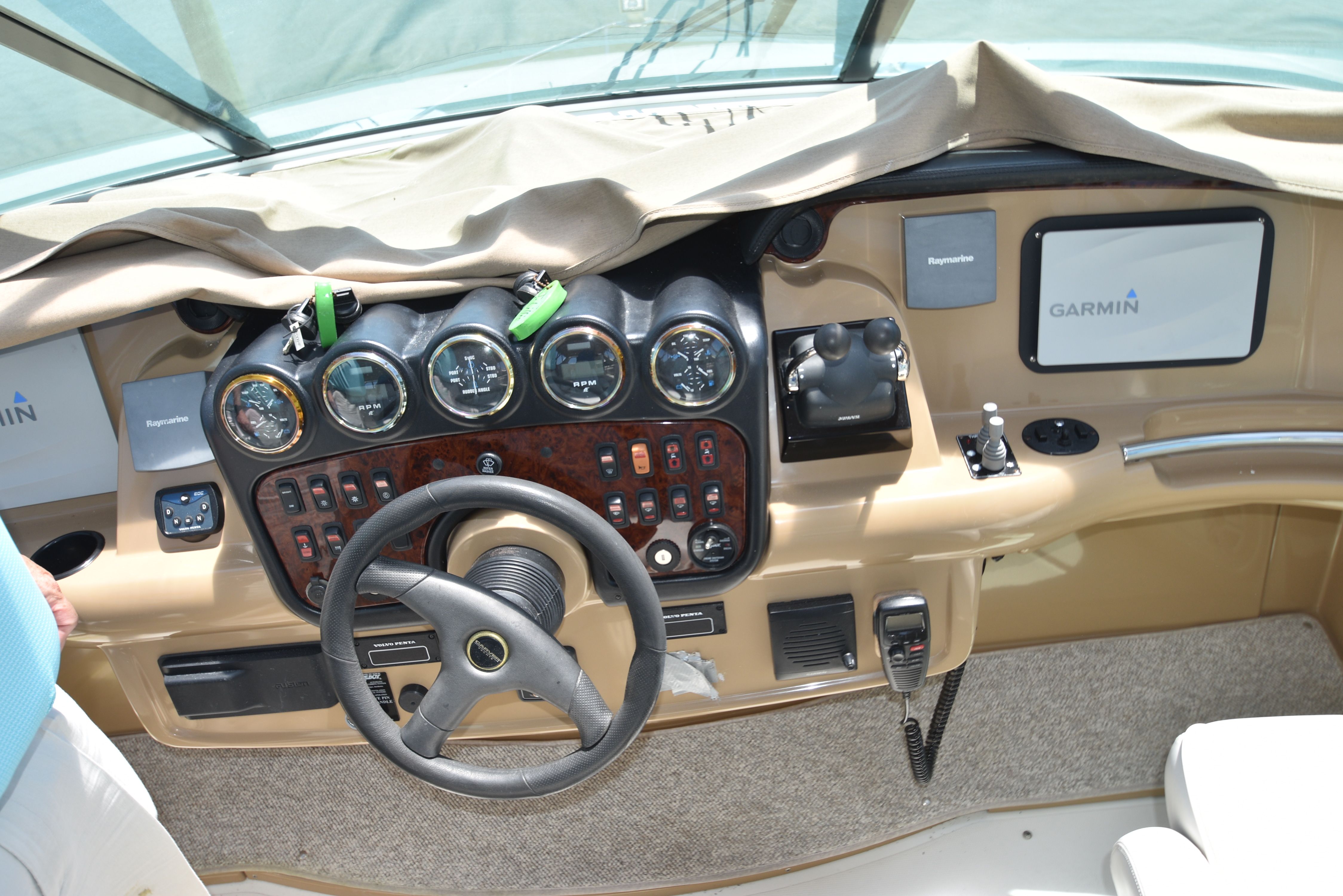 The cockpit of a 2004 Carver 466 Motor Yacht with steering wheel, gauges, and Garmin screens.