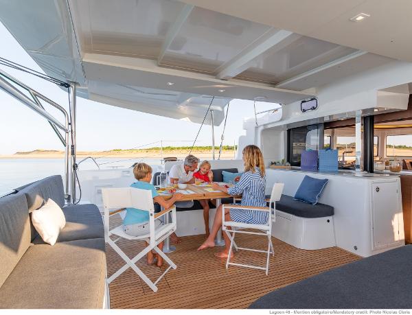 Family enjoying a meal on the deck of a 2025 Lagoon 46 ICONIC catamaran.