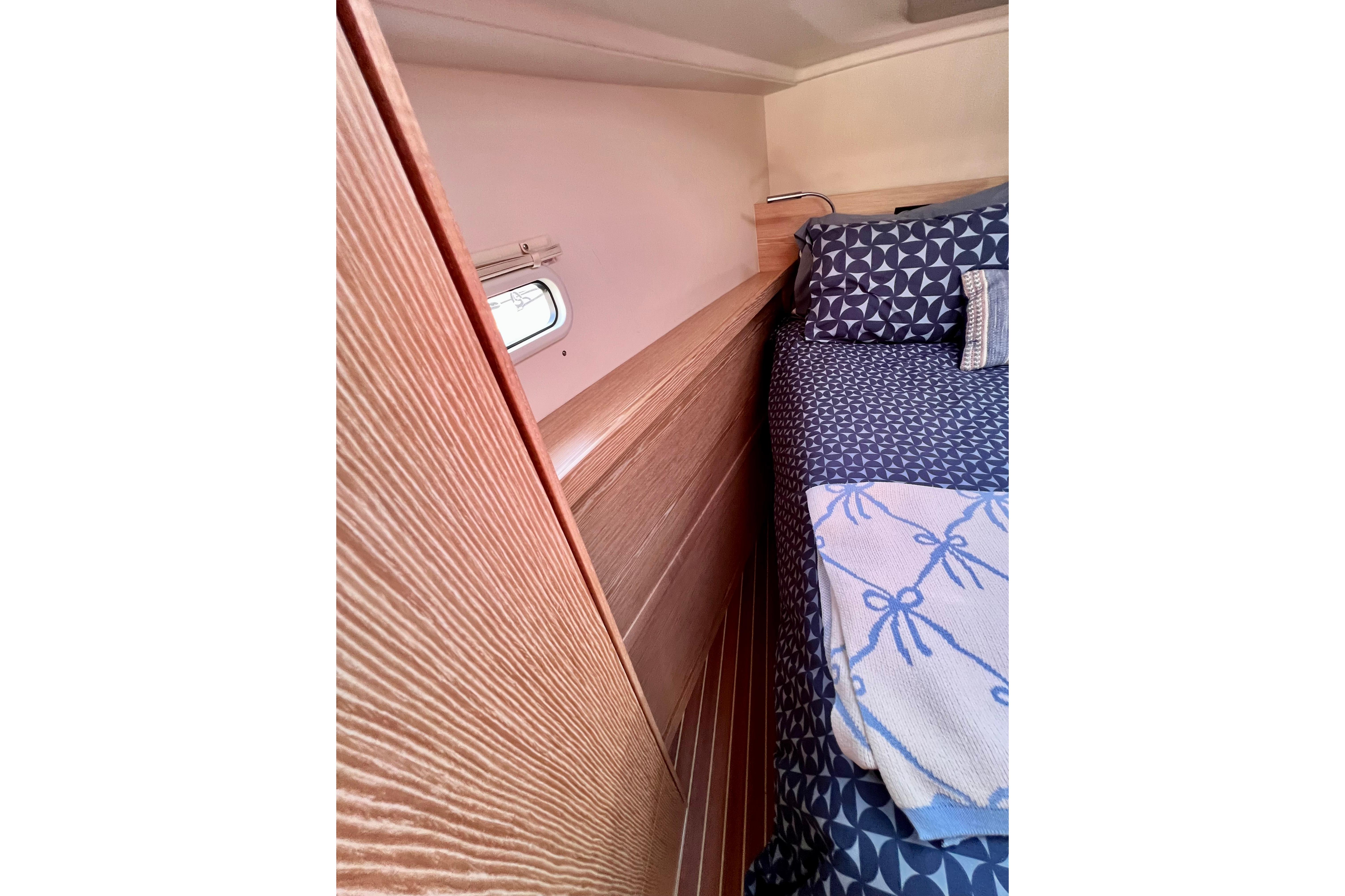 Interior cabin of 2016 Hanse 455 yacht with patterned bedding and wooden paneling.