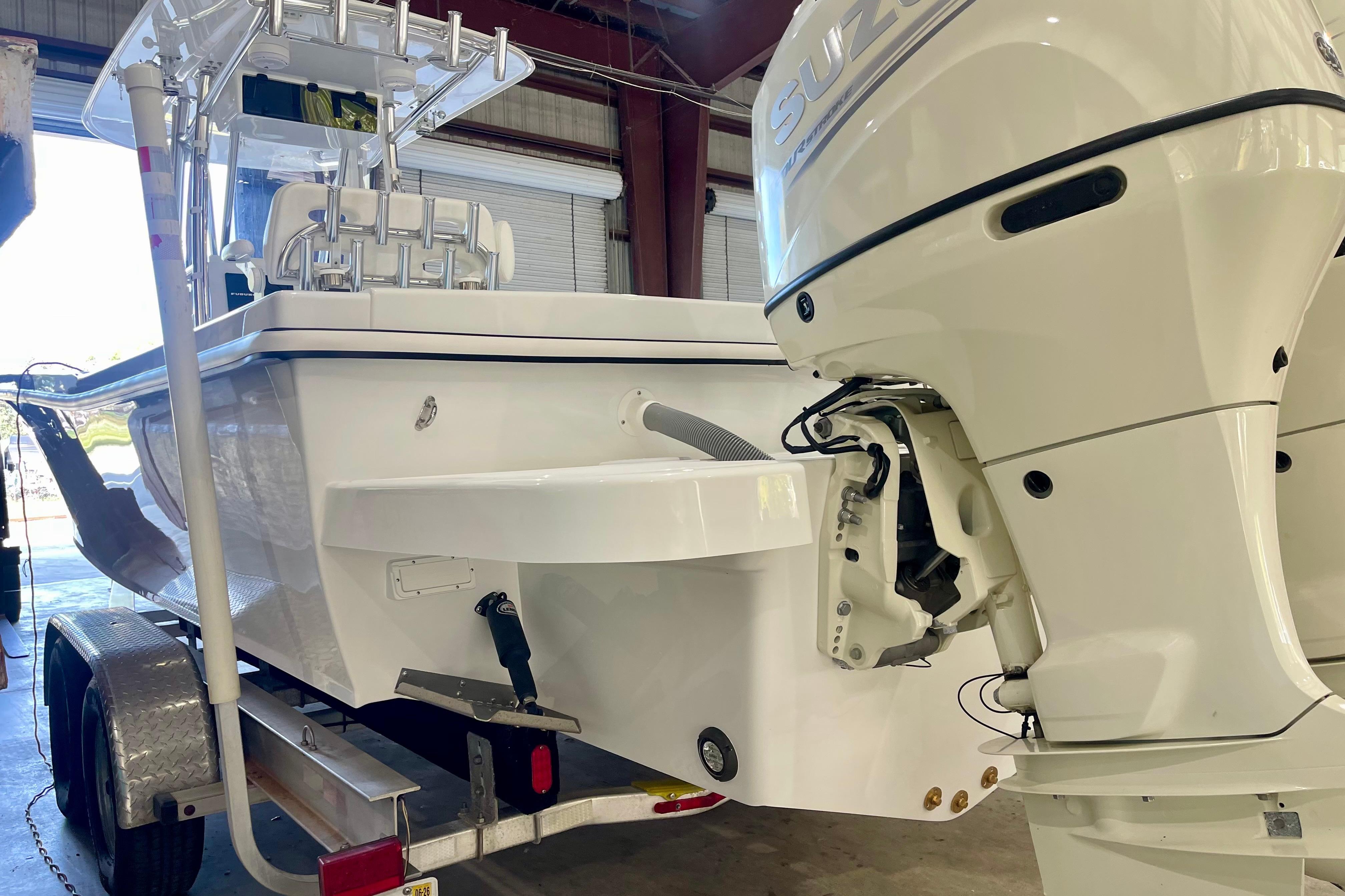 2025 Ocean Master 296 Center Console boat with Suzuki outboard motor in a garage.