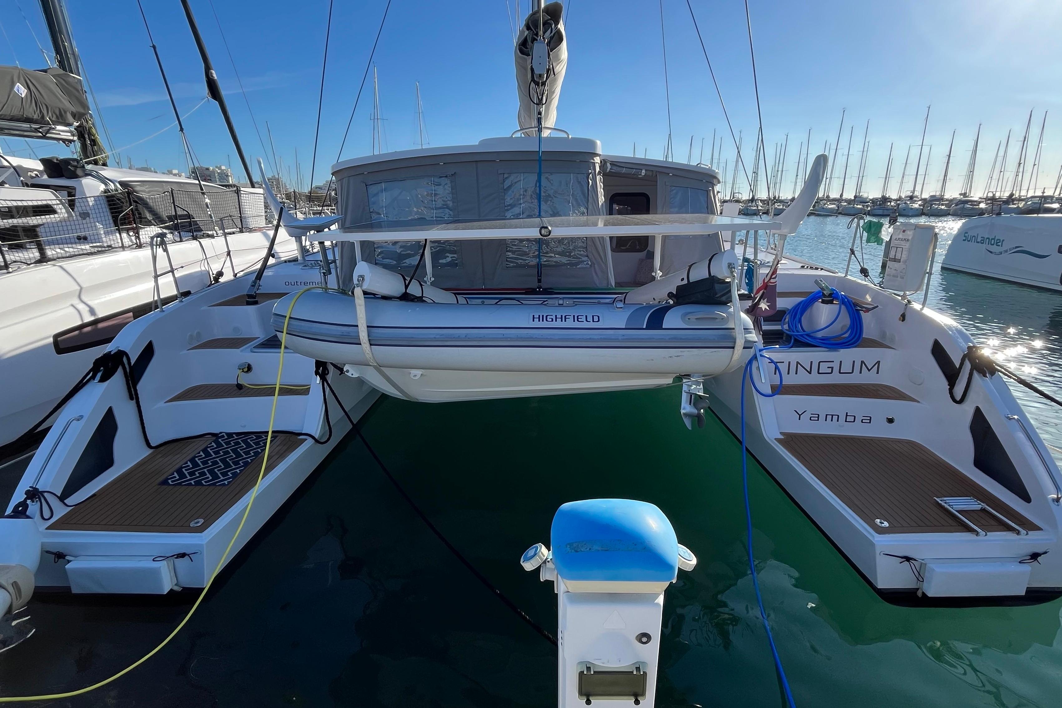 2024 Outremer 45 catamaran docked at marina, featuring a dinghy and spacious deck.