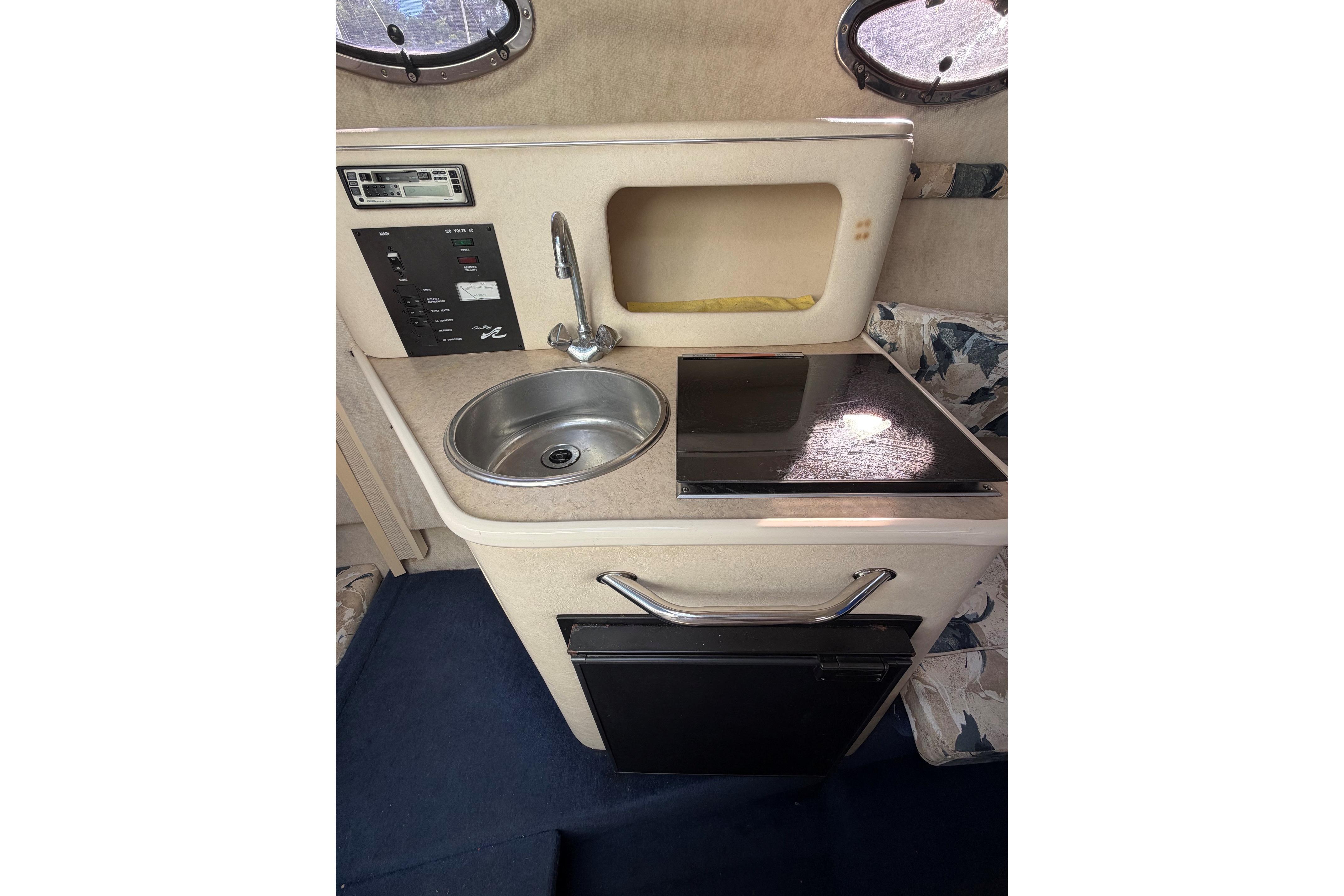Compact kitchenette in a 2000 Sea Ray 240 Sundancer boat, featuring sink and stove.