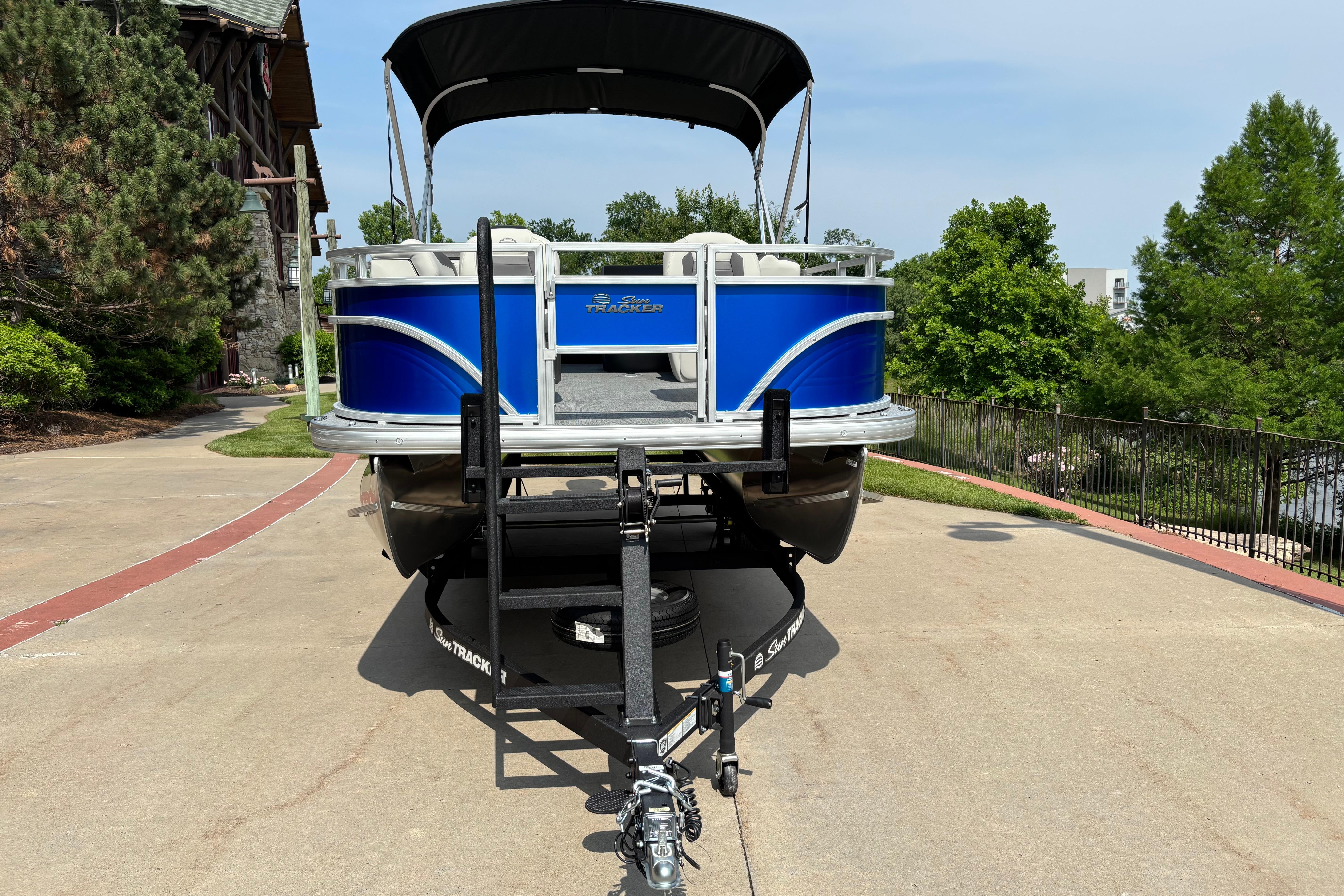 2026 Sun Tracker Fishin' Barge 20 DLX pontoon boat on trailer, parked outdoors.